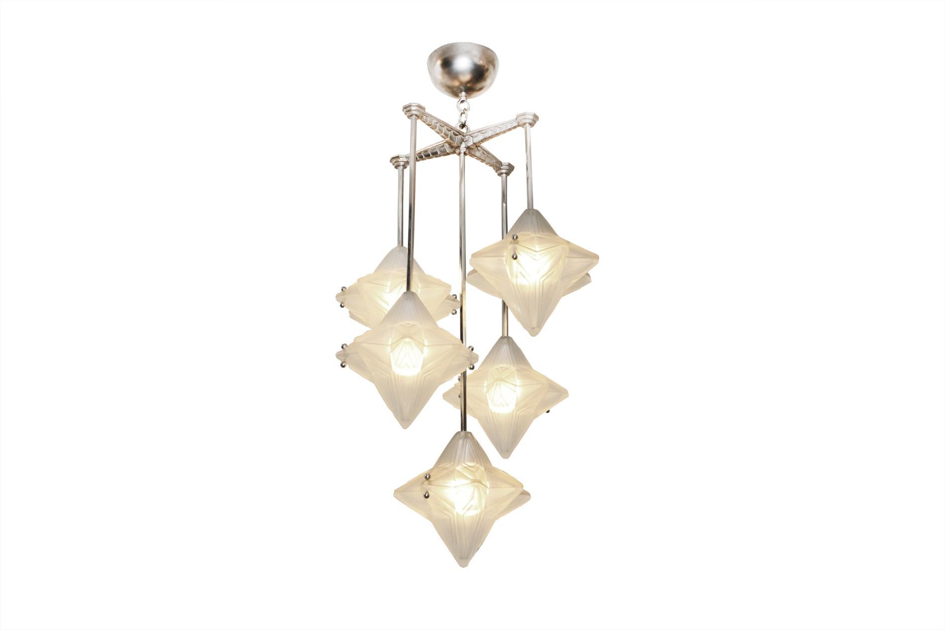 Französischer Art-Déco-Kronleuchter von Genet & Michon um 1930  mit 5 Lichtern auf verschiedenen Ebenen - Jede Lichtabdeckung, die aus zwei identischen Teilen aus gepresstem Glas besteht, erinnert an eine fallende Blume - Vernickelte Bronze. 