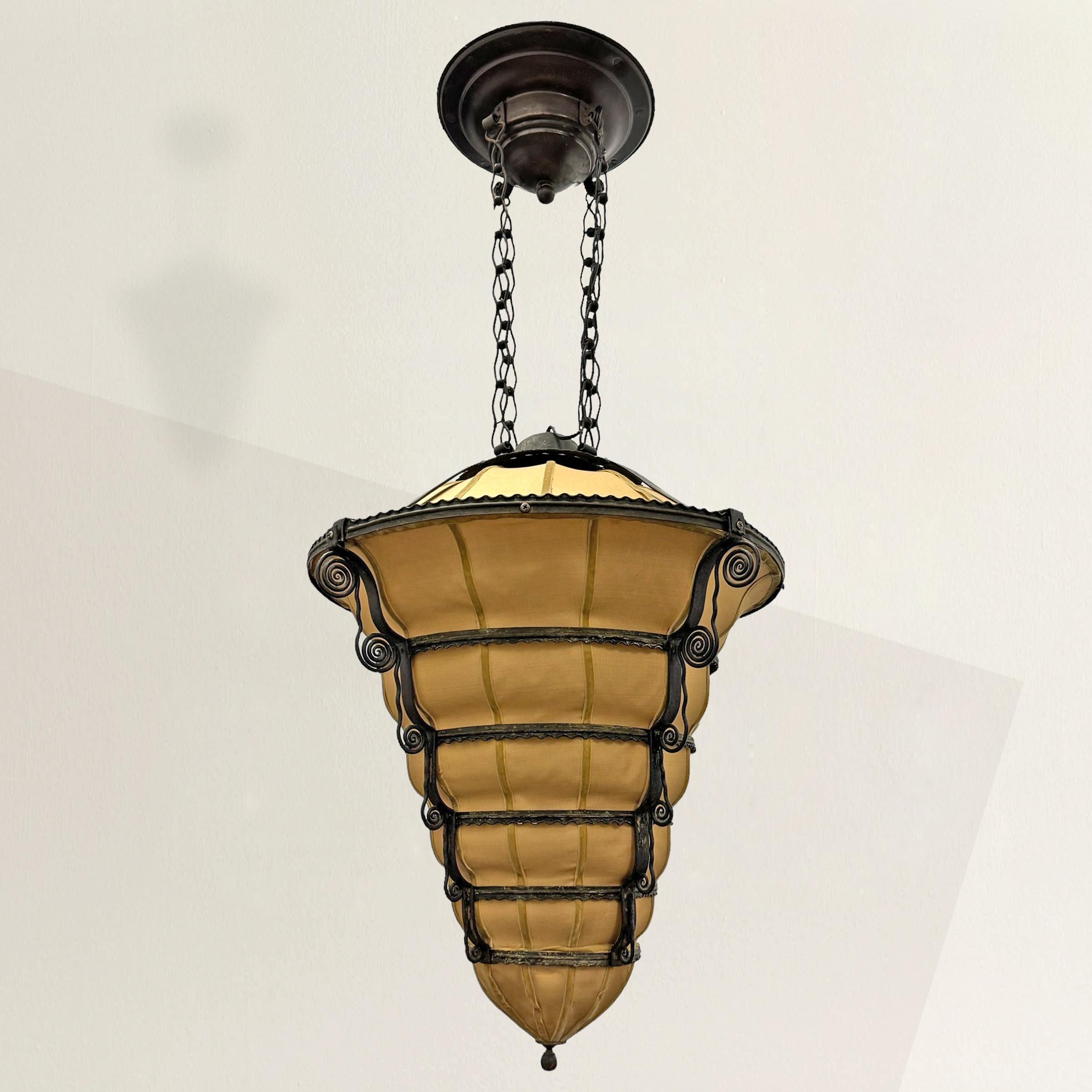 Ce superbe lustre Art déco français des années 1930 est un chef-d'œuvre de design. Il présente une remarquable forme de ruche en fer forgé, ornée d'élégants tourbillons de fer qui tombent en cascade le long de ses flancs. Sa silhouette saisissante