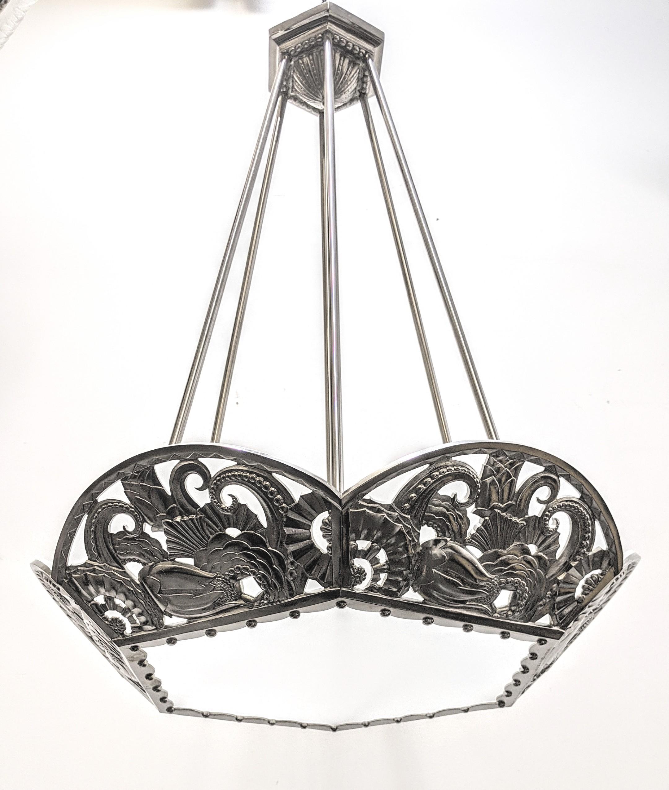 French Art Deco bronze hexagonal-shaped chandelier with multi-dimensional intertwining geometric flower motif details. Each decorative side plack has a flat frosted glass panel encased within, with a matching large center panel. The chandelier has