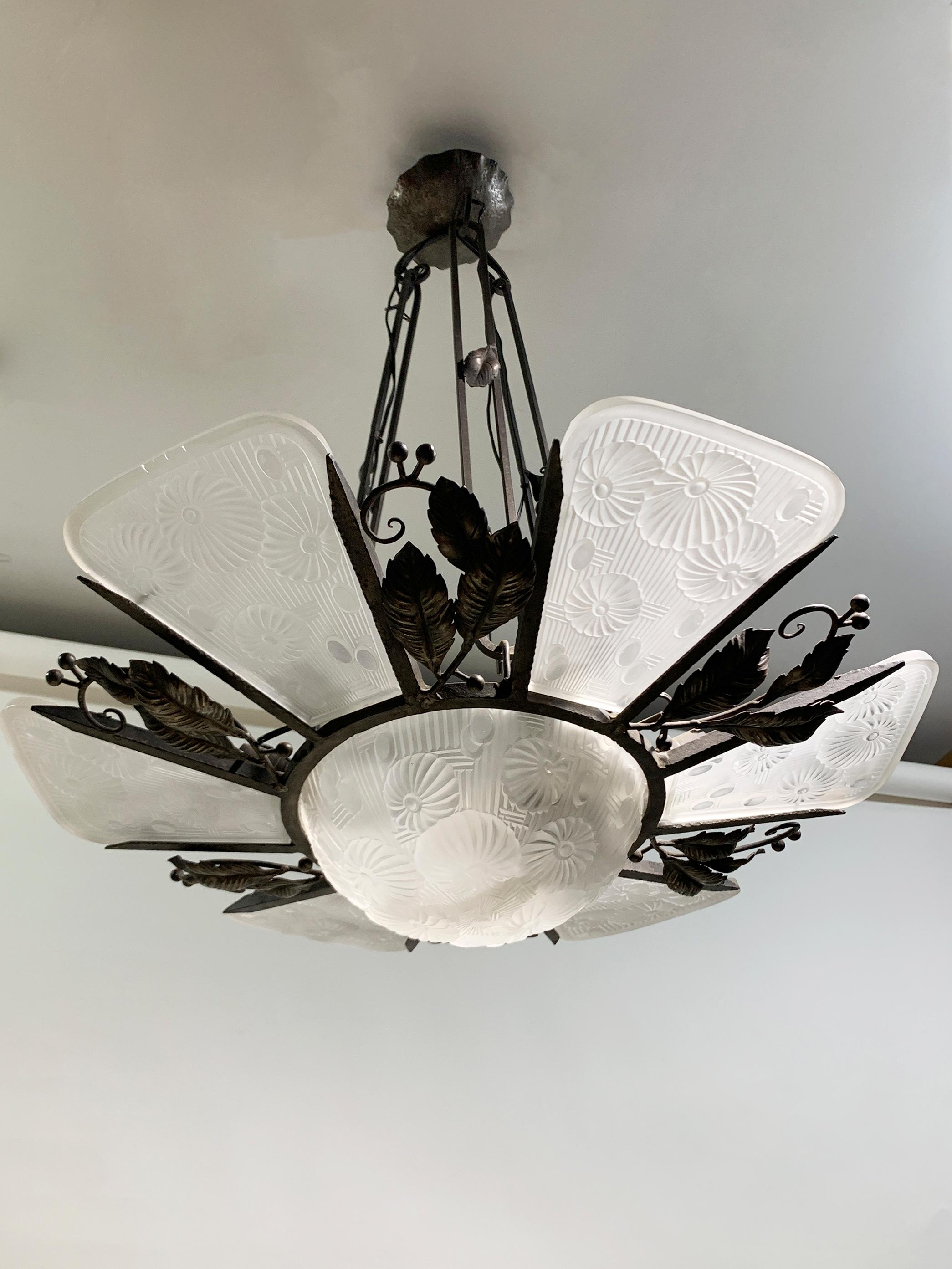 Questo straordinario lampadario Art Deco francese degli anni '30 è un ottimo esempio dell'intricata maestria dell'epoca, che fonde un design opulento con un'eleganza funzionale. Il lampadario presenta una ciotola centrale e sei pannelli di vetro