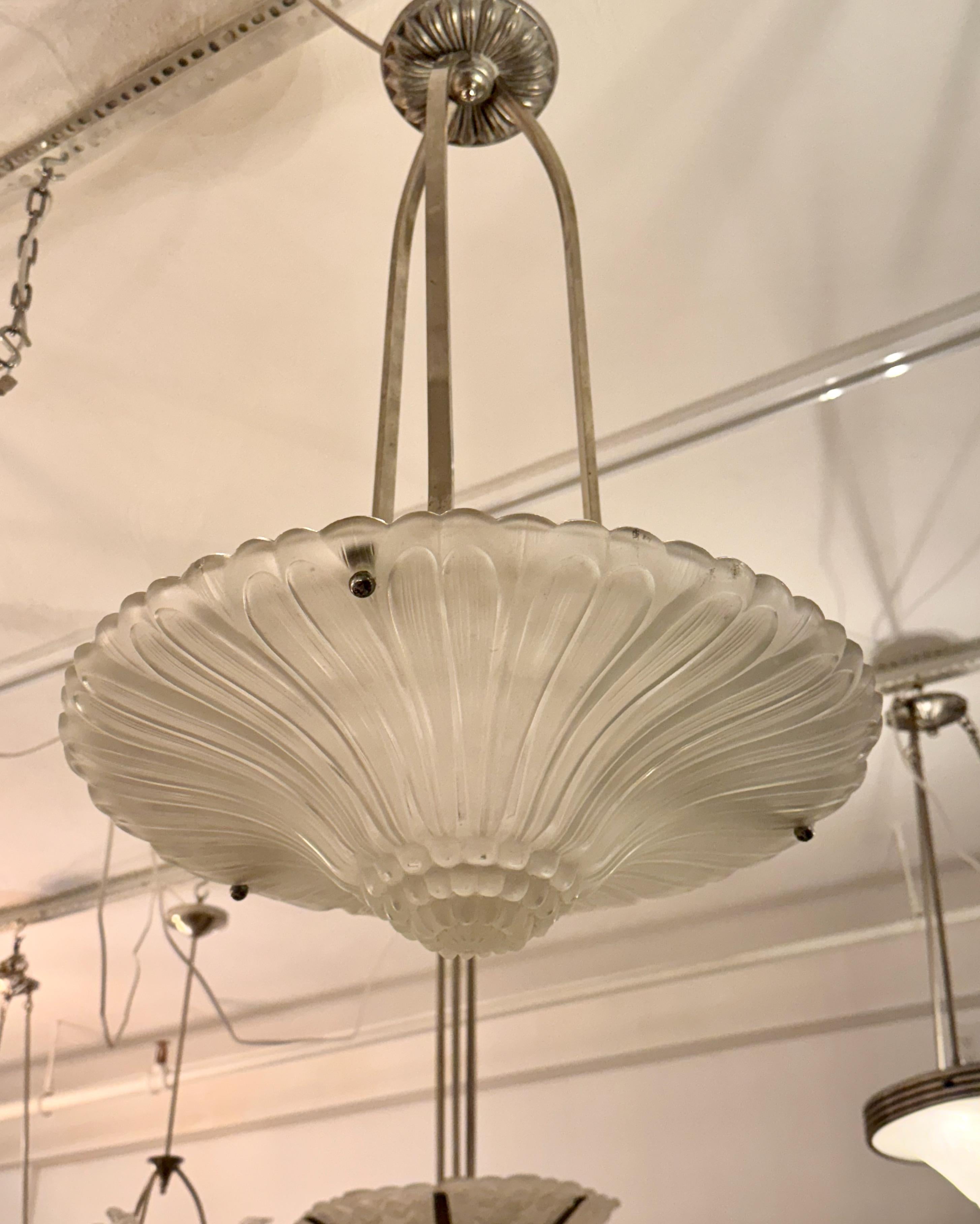 French Art Deco chandelier by Georges Leleu. With beautiful clear frosted glass bowl with geometric motif. Held by three nickel metal rods and matching ceiling plate. Has been rewired for American use. Two candelabra sockets.


 