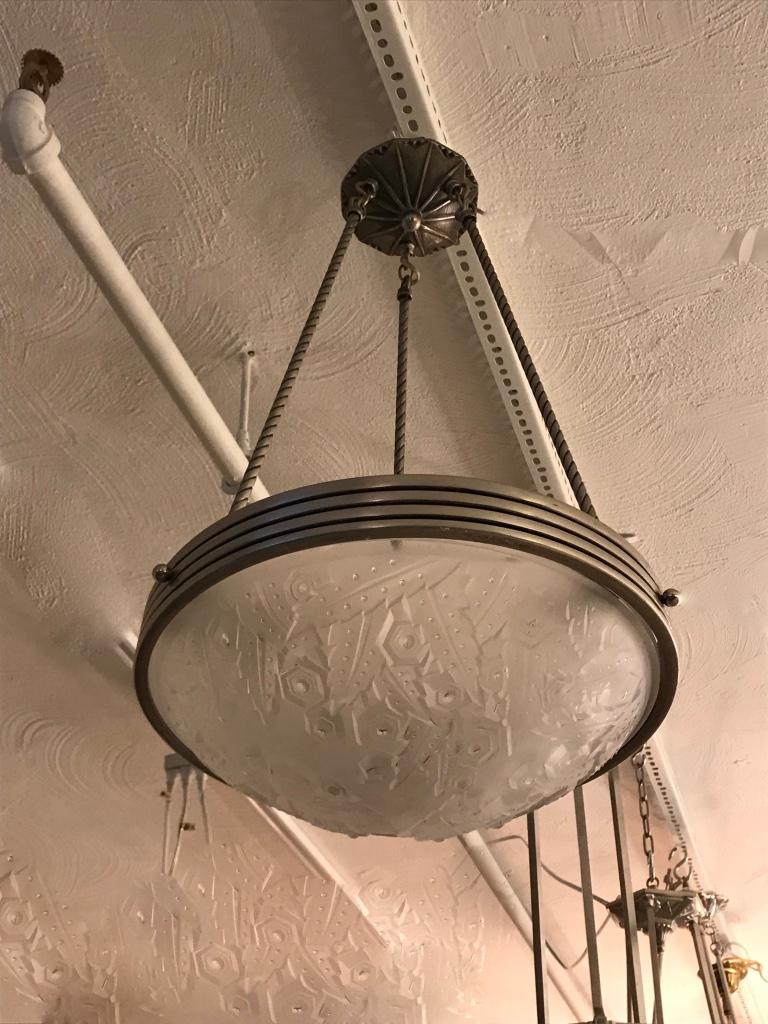 Stunning French Art Deco chandelier signed by Muller Frères Luneville. With beautiful clear frosted glass bowl with geometric motif. Held by nickel plated bronze round ribbed frame and three rods with matching ceiling plate. Re plating upon request.