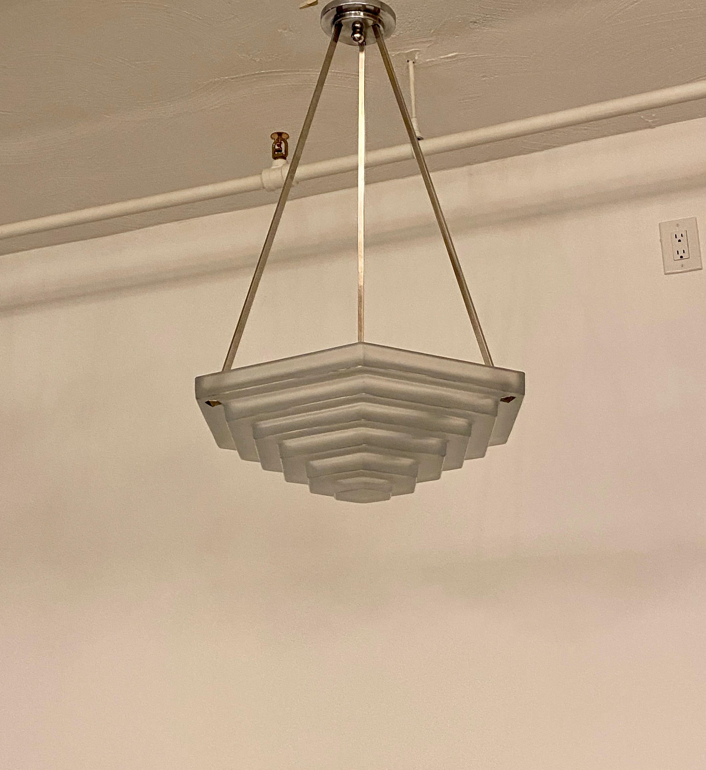 French Art Deco chandelier signed by French Artist Degue. Having one large stepped geometric glass shade. Held by three nickel rods. Has been rewired for American use with one medium base socket.