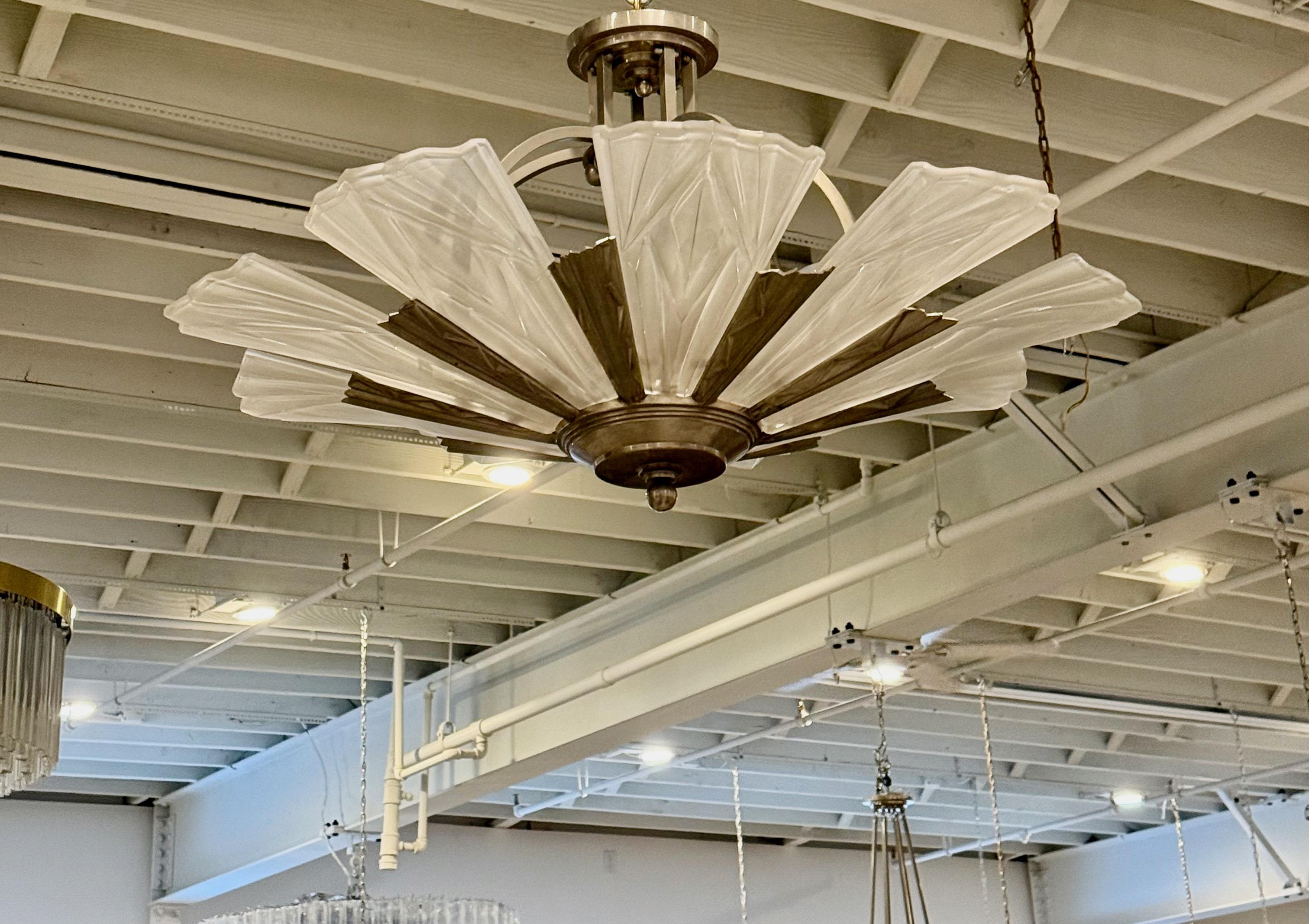 French Art Deco chandelier signed by the famous French artist David Gueron Degue. Having nine clear frosted geometric glass panels all signed by Degue. The glass panels rest on a nickel Deco design frame. Geometric motif throughout the entire frame