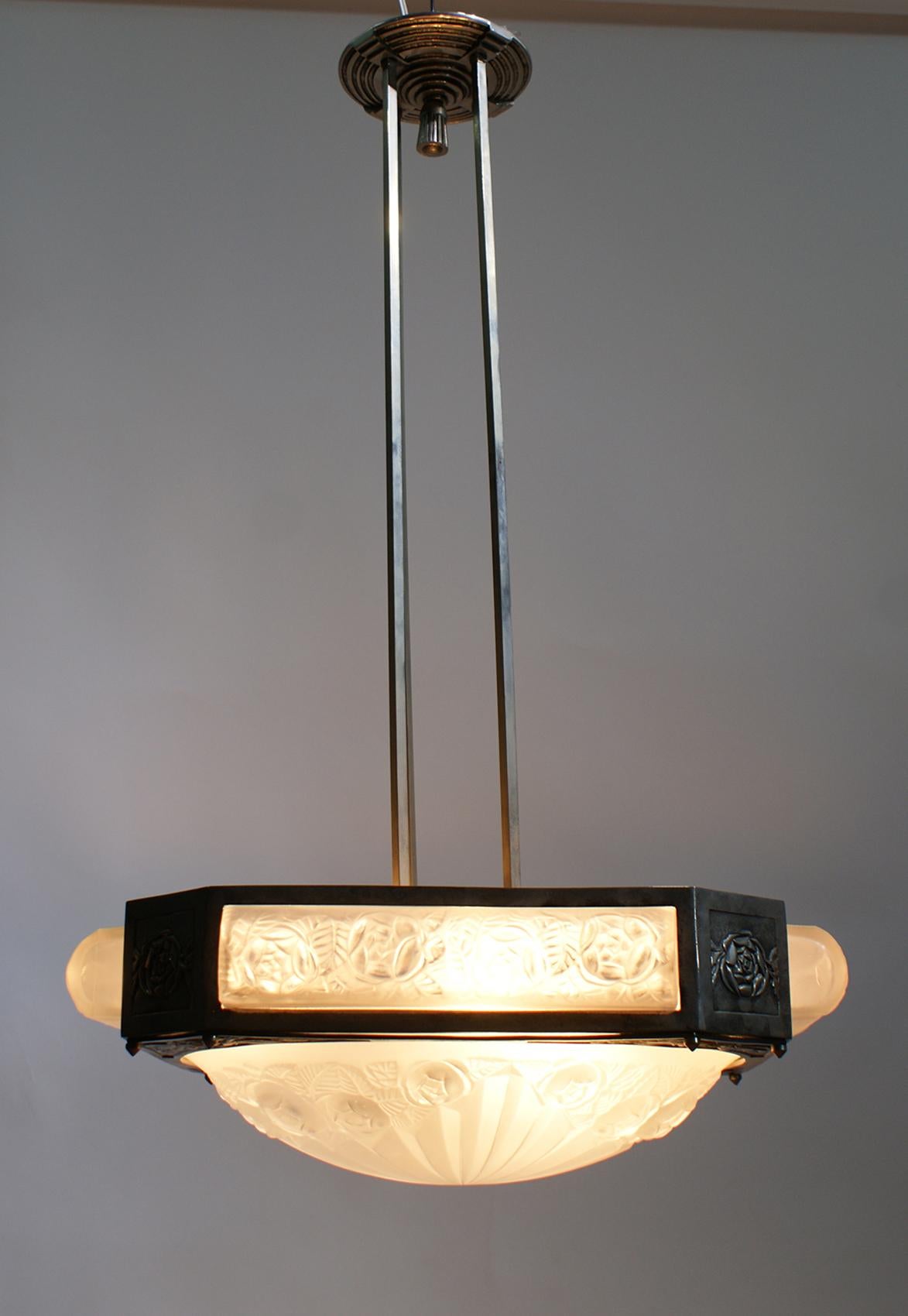 Stunning French Art Deco chandelier created by the French artist Degué. In a square nickel bronze frame embracing a center coupe marked Degué, with four matching oblong shades marked with numbers “501”. All shades are in clear frosted glass with