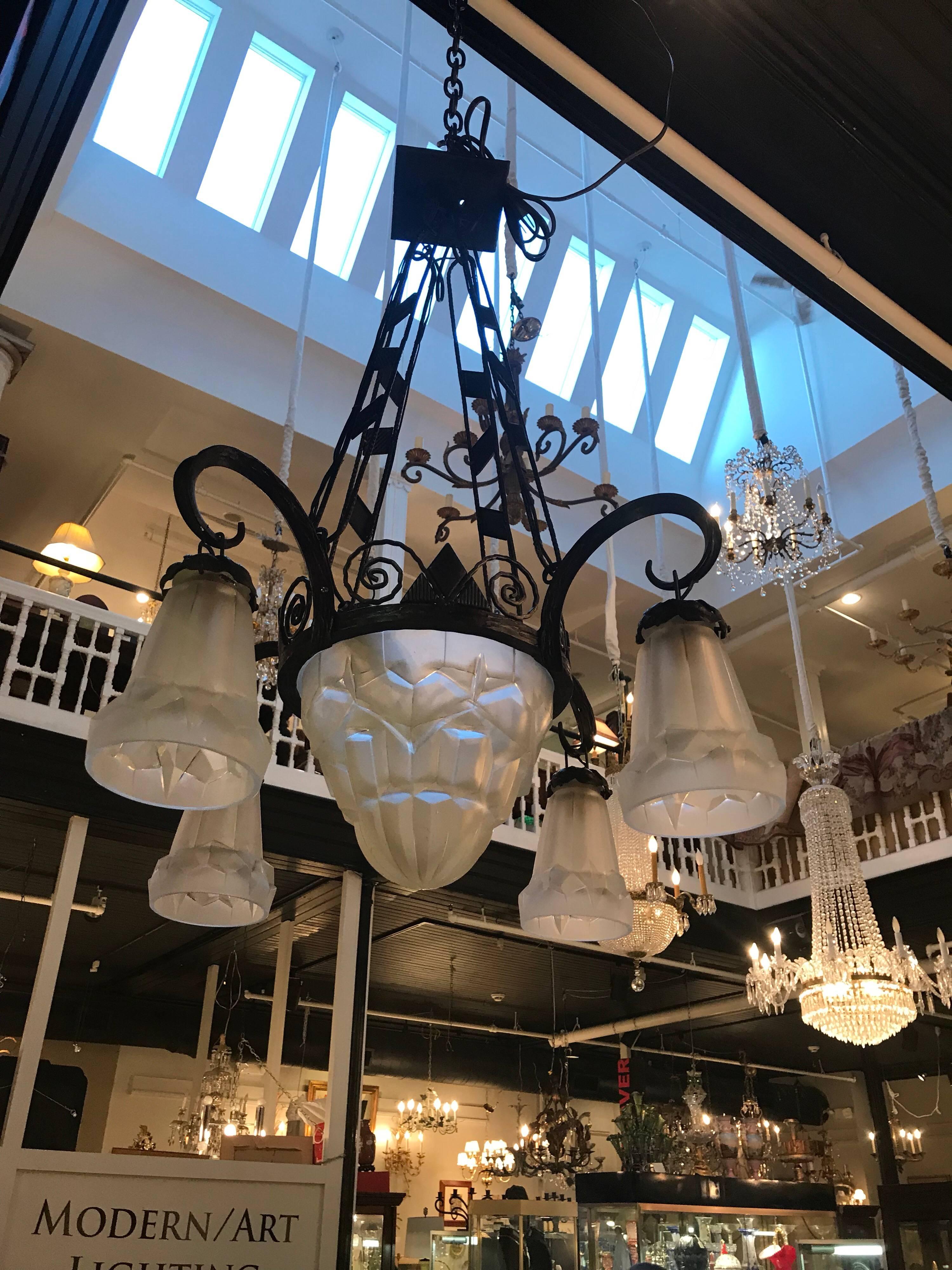 French Art Deco chandelier signed Degue. The patinated iron frame with frosted ice cube pattern shades and center bowl. 

There are a couple of very minor nibbles to the inner glass edge that fits right inside the metal mounts not visible when