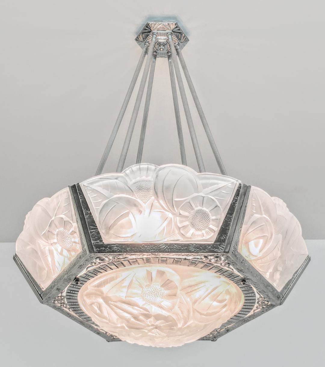 A French Art Deco chandelier with six-sided shades embracing a matching round center coupe in clear frosted molded shades. Each shade is signed by the French artist Degué. Flower motif polished details mounted on a nickeled wrought iron streamlined