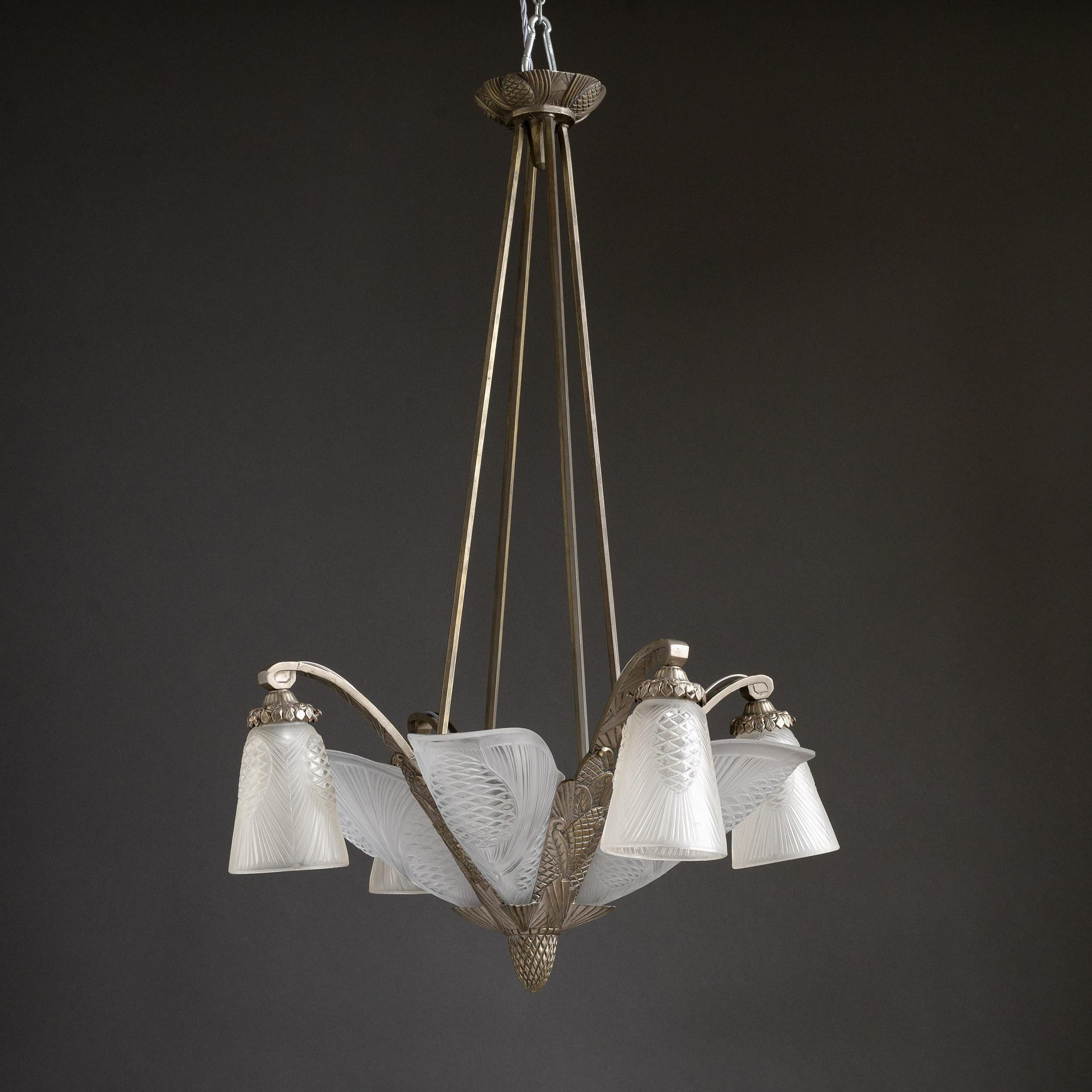 A French Art Deco chandelier by Degué, 1930s, the frame of nickel plated brass with moulded and frosted glass shades, with light fitments to the body as well as each of the four arms. Re-wired to UK specifications.

Dimensions:	90cm (35½