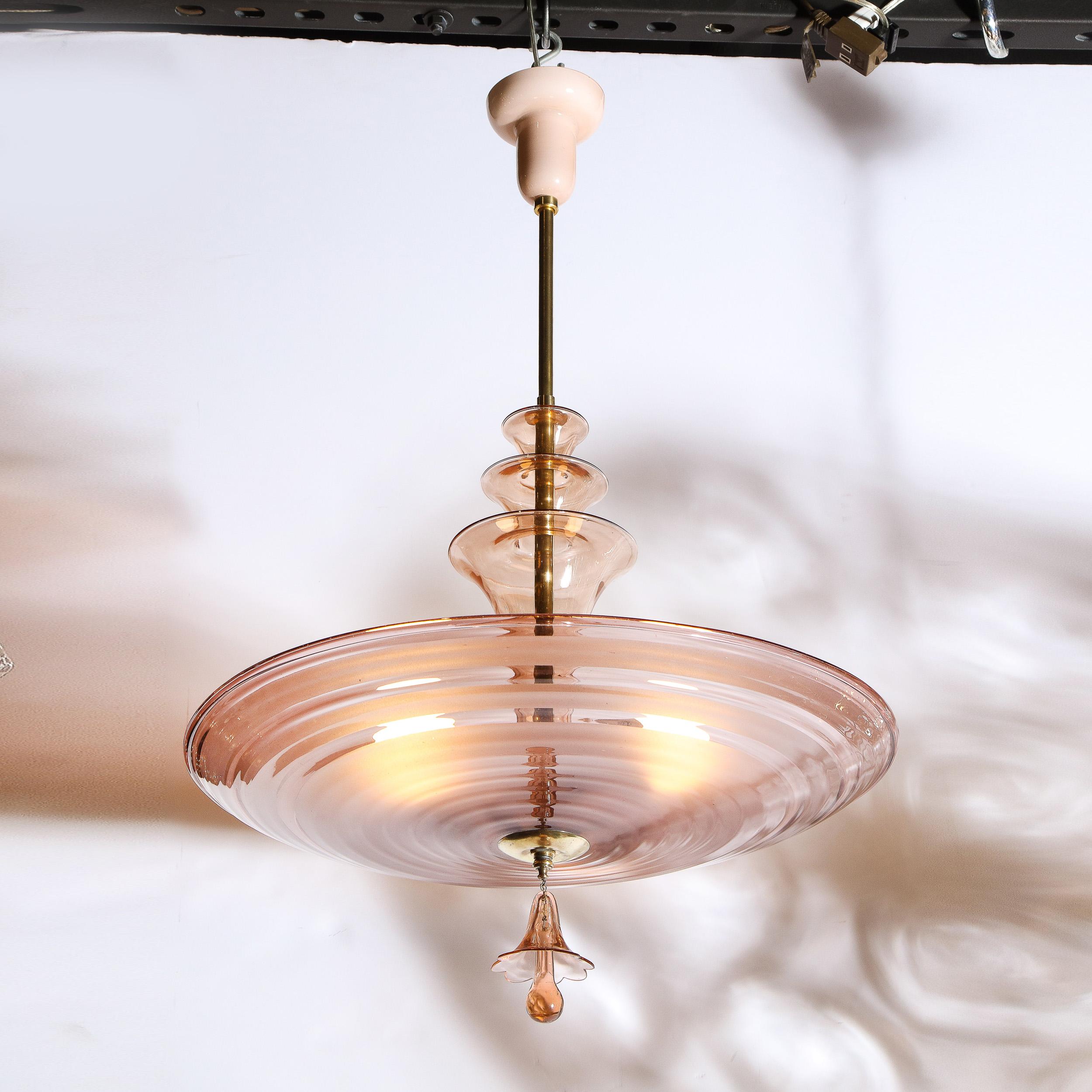 This sophisticated, Art Deco, Machine Age chandelier was created in the France circa 1940. It features a domed, concave bottom composed of alternating frosted and transparent glass. The chandelier attaches to a nippled, opaque glass canopy via the