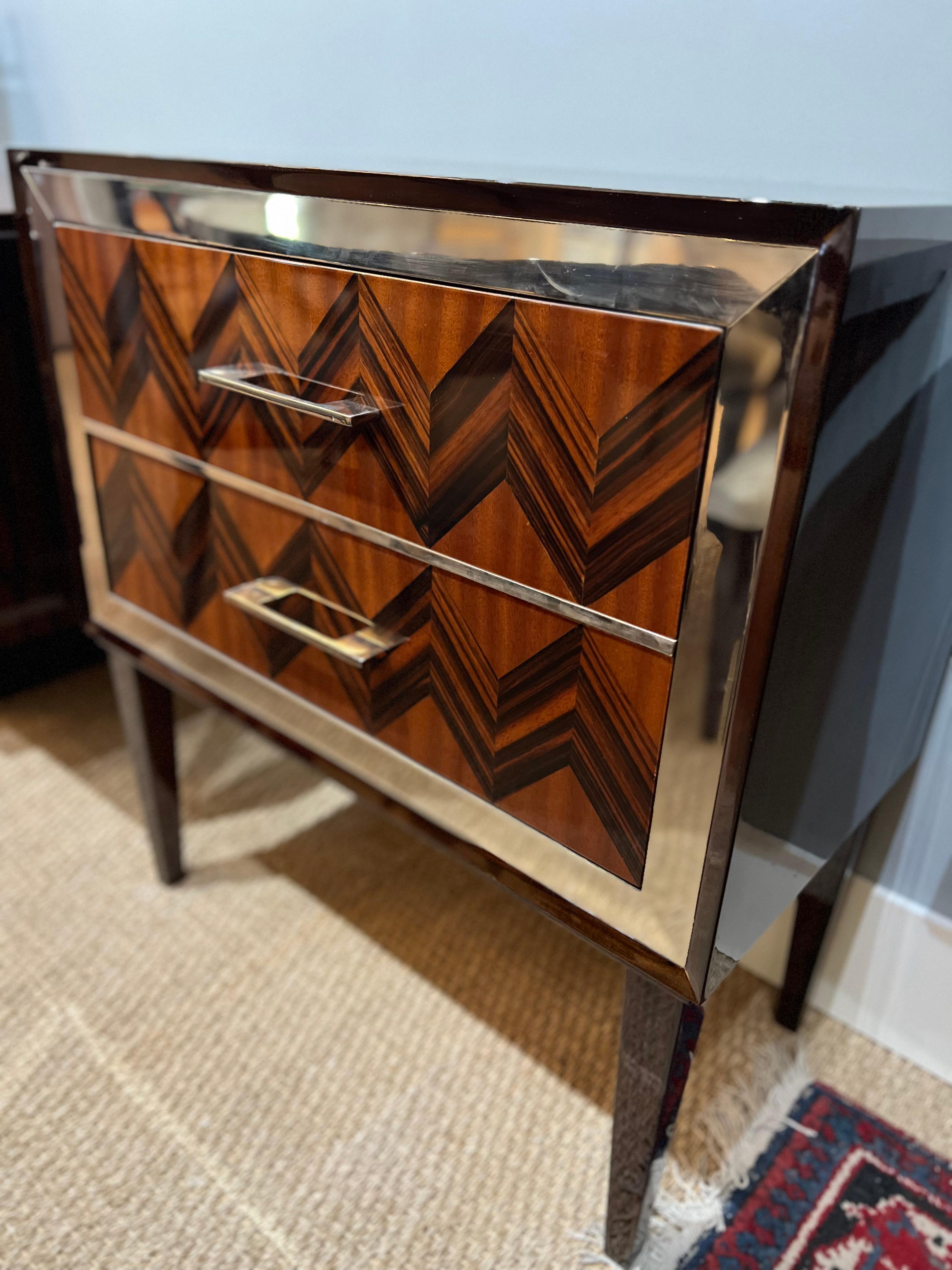 Commode / table de nuit en palissandre et acajou. Elle comporte 2 tiroirs spacieux, surélevés par 4 pieds allongés. La façade des tiroirs est décorée d'un motif géométrique et entourée d'un ruban en laiton. 

Très bon état, restauré.
France,