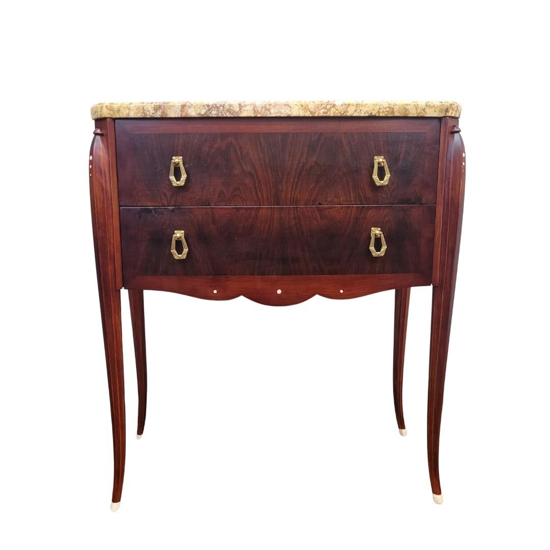 Cómoda única de madera preciosa con incrustaciones de hueso como pequeñas burbujas en la parte superior de cada pata y en el faldón recortado, pequeños círculos que añaden diseño y exquisitez a la pieza.
Con un perfil rectangular, está diseñada como