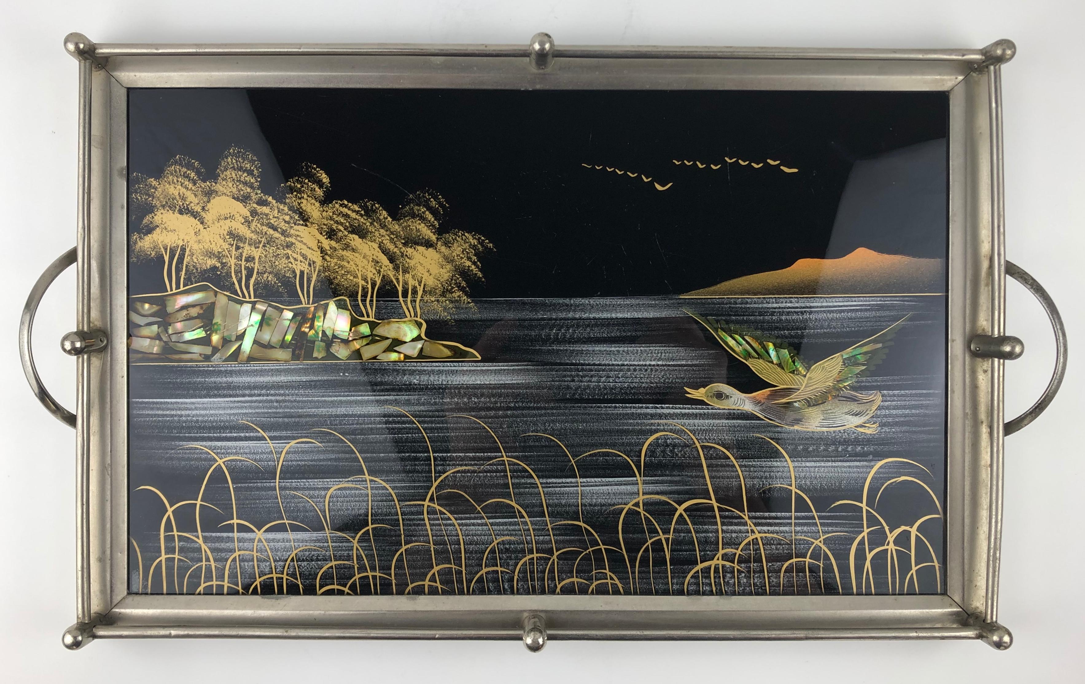 Beautiful French Art Deco chrome serving tray with hand inlayed mother of pearl decor artistically placed under glass. This piece is particularly stunning with intricate details of the birds in flight, a pond or ocean, rock Formations and swaying