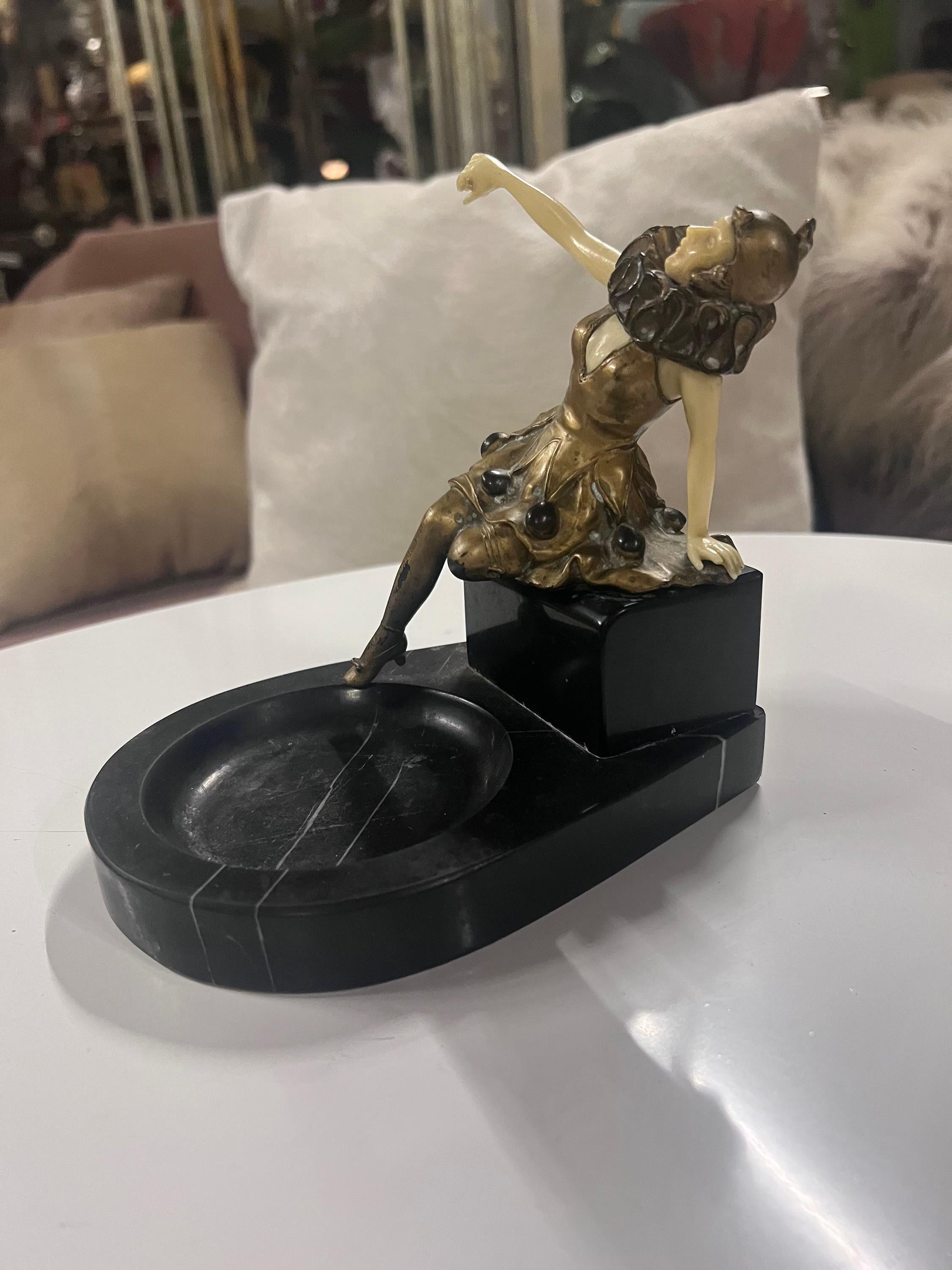 Antike Französisch Art Deco Chryselephantine Bronze Harlekin Posing auf Marmorsockel Aschenbecher  

Dieser exquisite französische Art-Déco-Aschenbecher ist ein Zeugnis der Opulenz und Handwerkskunst des frühen 20. Sie ist im Chryselephantine-Stil