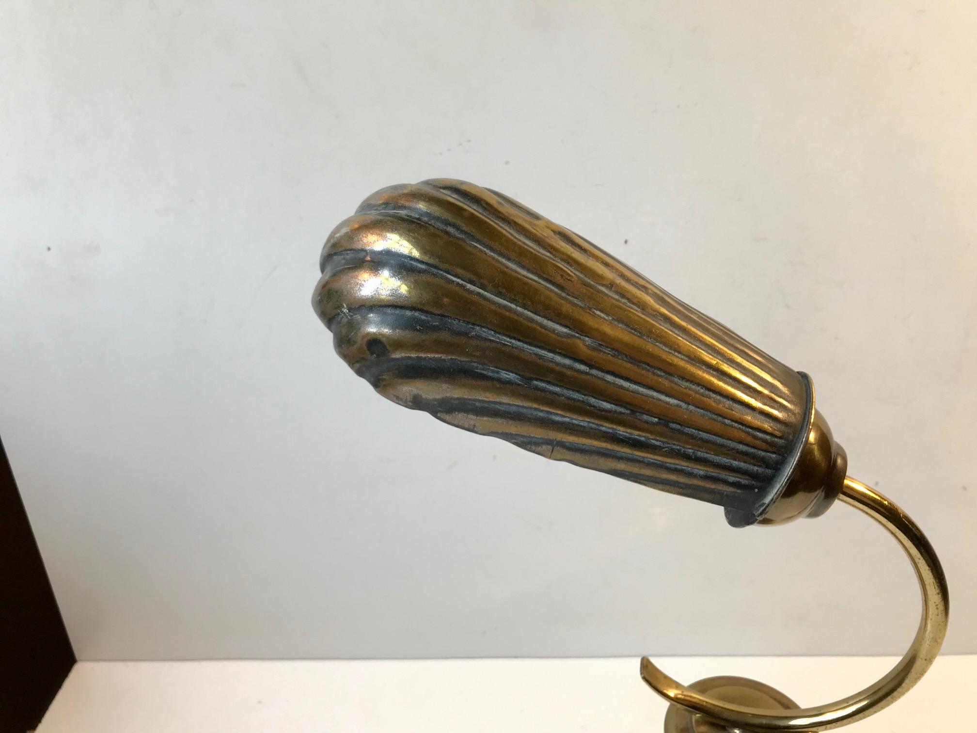 A very early table light with adjustable clam shell shade. Besides the centerpiece in stained oak everything is made from brass. It still has its original French bajonet socket but the cord and on/of switch has been replaced to accommodate modern