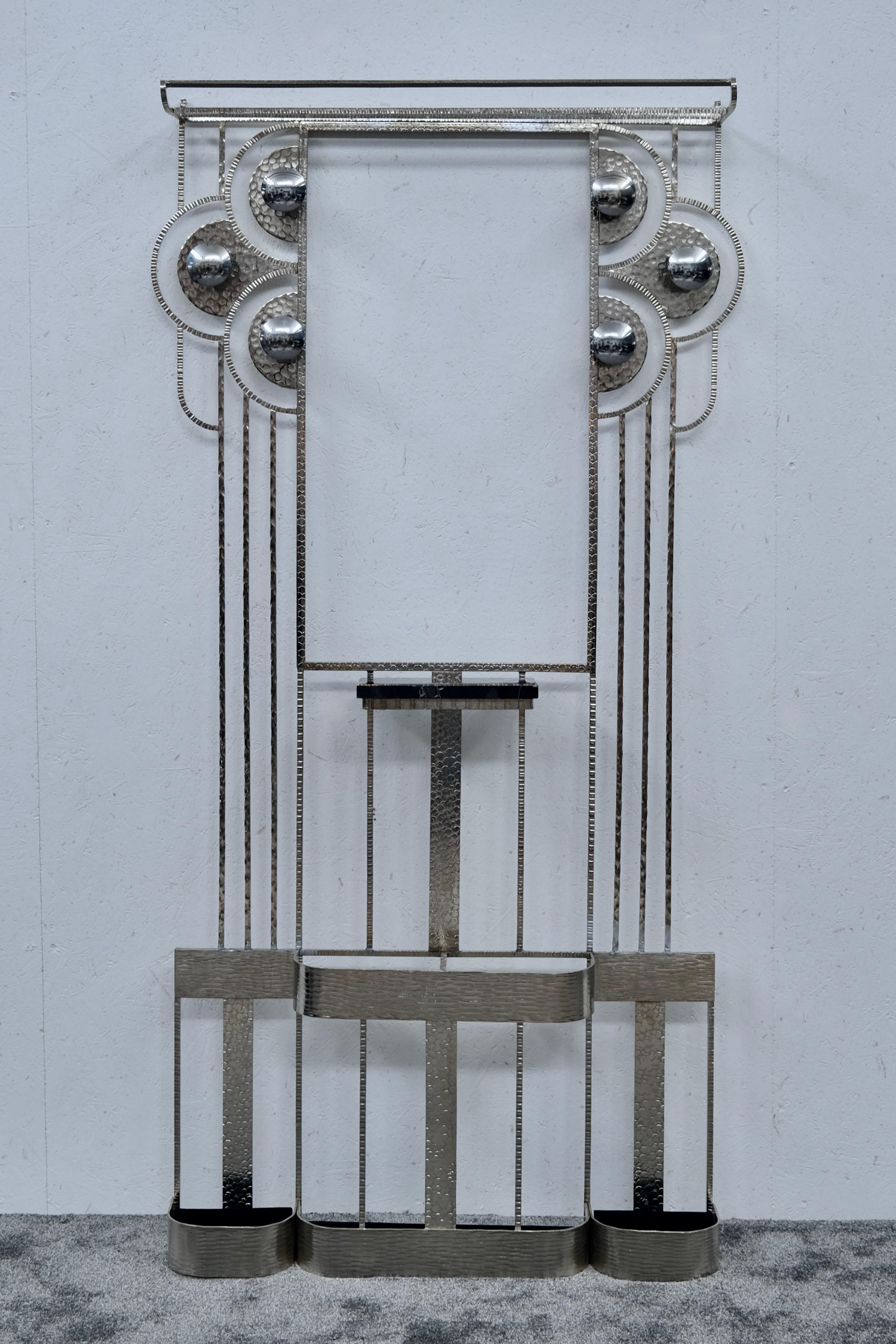 Este impresionante perchero Art Déco francés de los años 30 es un ejemplo perfecto de la refinada artesanía en metal de la época. De hierro forjado macizo y recién niquelado, presenta un llamativo juego de texturas martilladas, ornamentos circulares