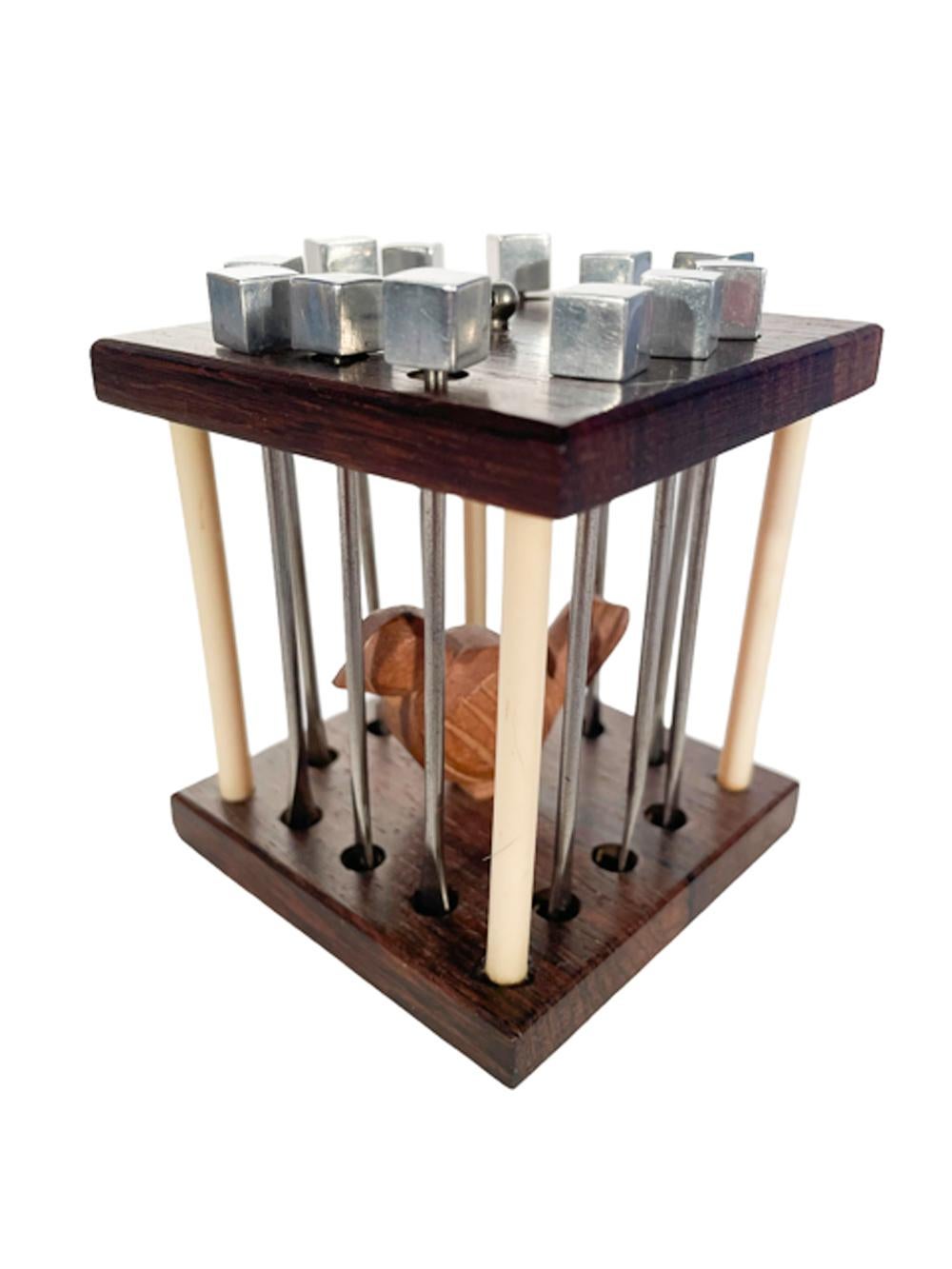 French Art Deco caged bird cocktail pick set, two pieces of wood supported at the corners with white Bakelite poles creating an open cube, the chrome picks with block tops hang three to a side forming the bars and caging the carved wood bird inside.