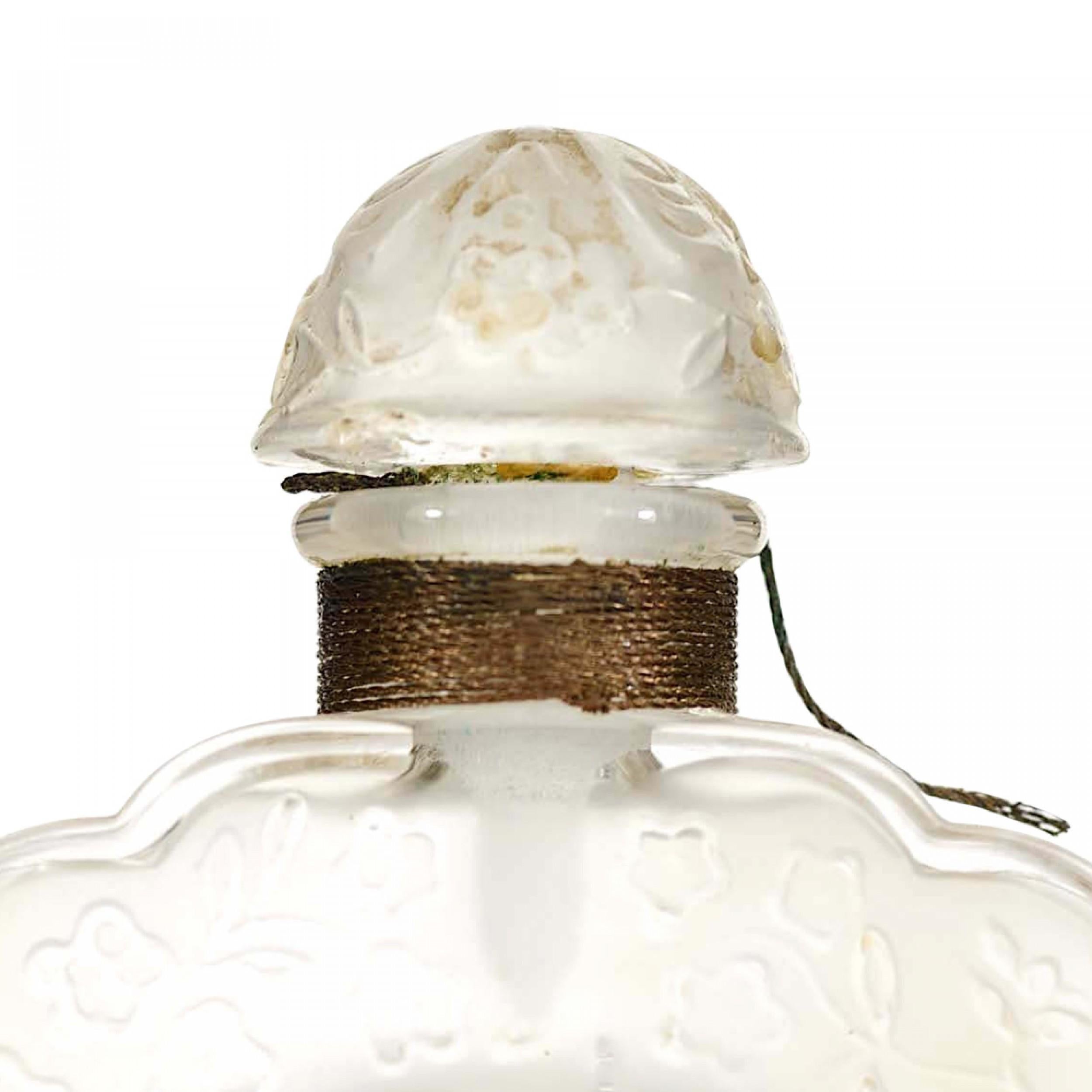 Bottiglia di profumo in vetro trasparente smerlato Art Deco francese (COEUR JOIE di Nina Ricci) con apertura a forma di cuore al centro, disegno floreale in rilievo e tappo a forma di cupola (firmata Lalique 