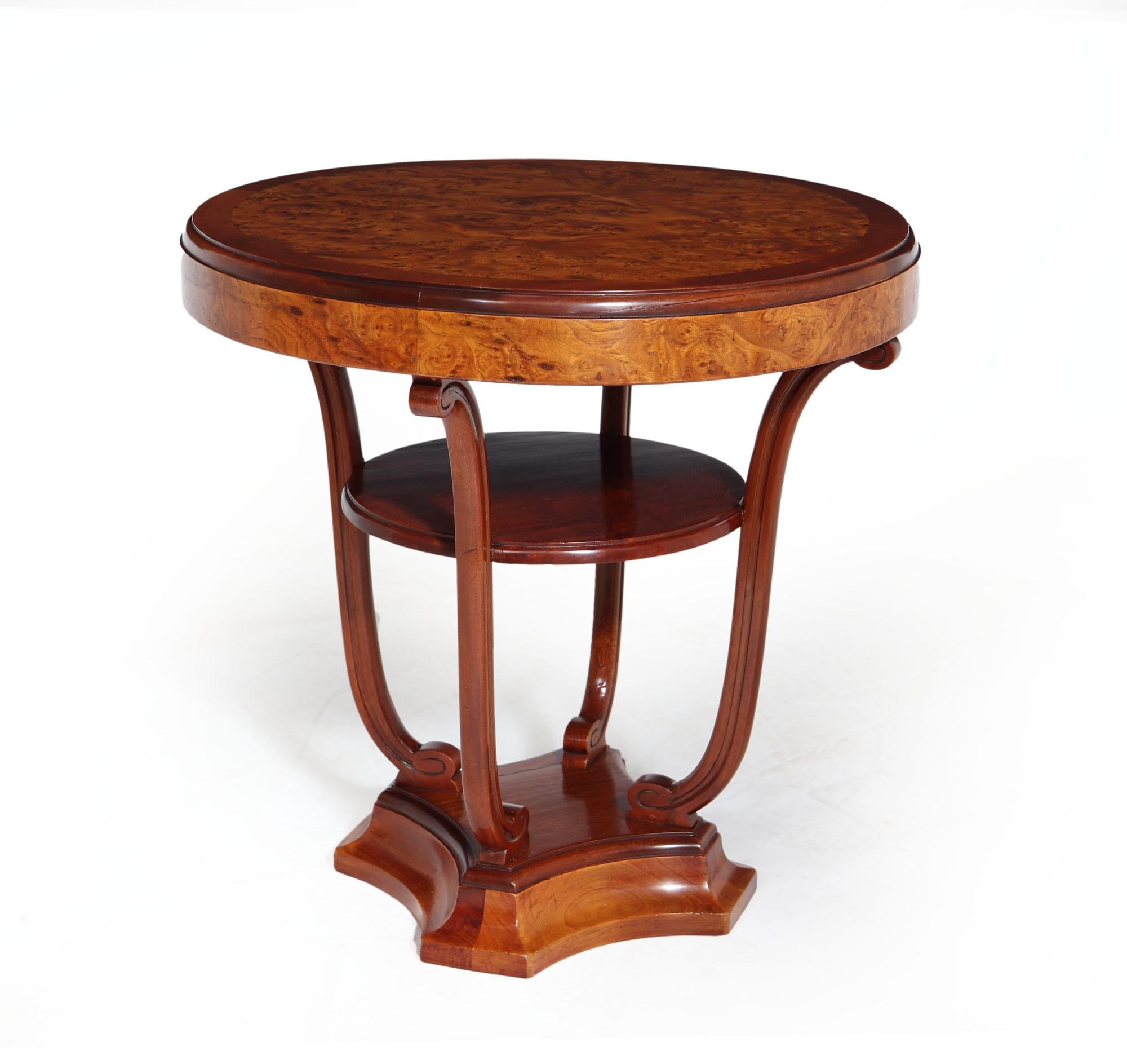 An exceptional quality and style centre table by Maurice Dufrene produced in Paris France 1920-1925 this table has a quartered burr walnut with solid mahogany surround, The table has a centre shelf that is supported by four solid mahogany gently