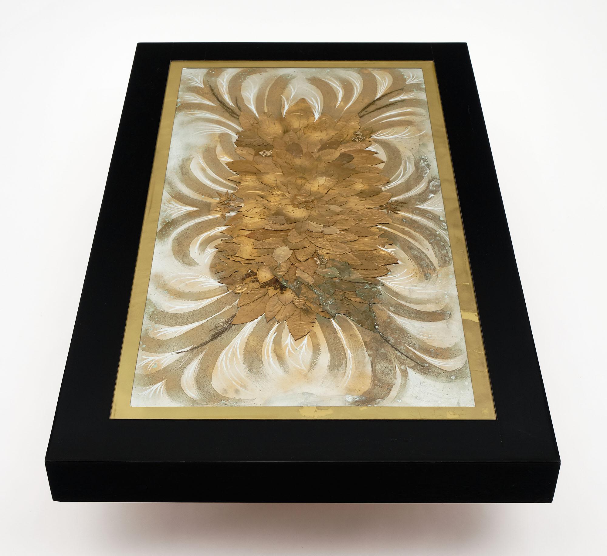 French Art Deco ebonized wood coffee table with glass top. It is made of ebonized oak and features gold leafed edges to the glass covering a gold leaf and natural decor decoration on aluminum. This piece of art is signed by N. Maillard.