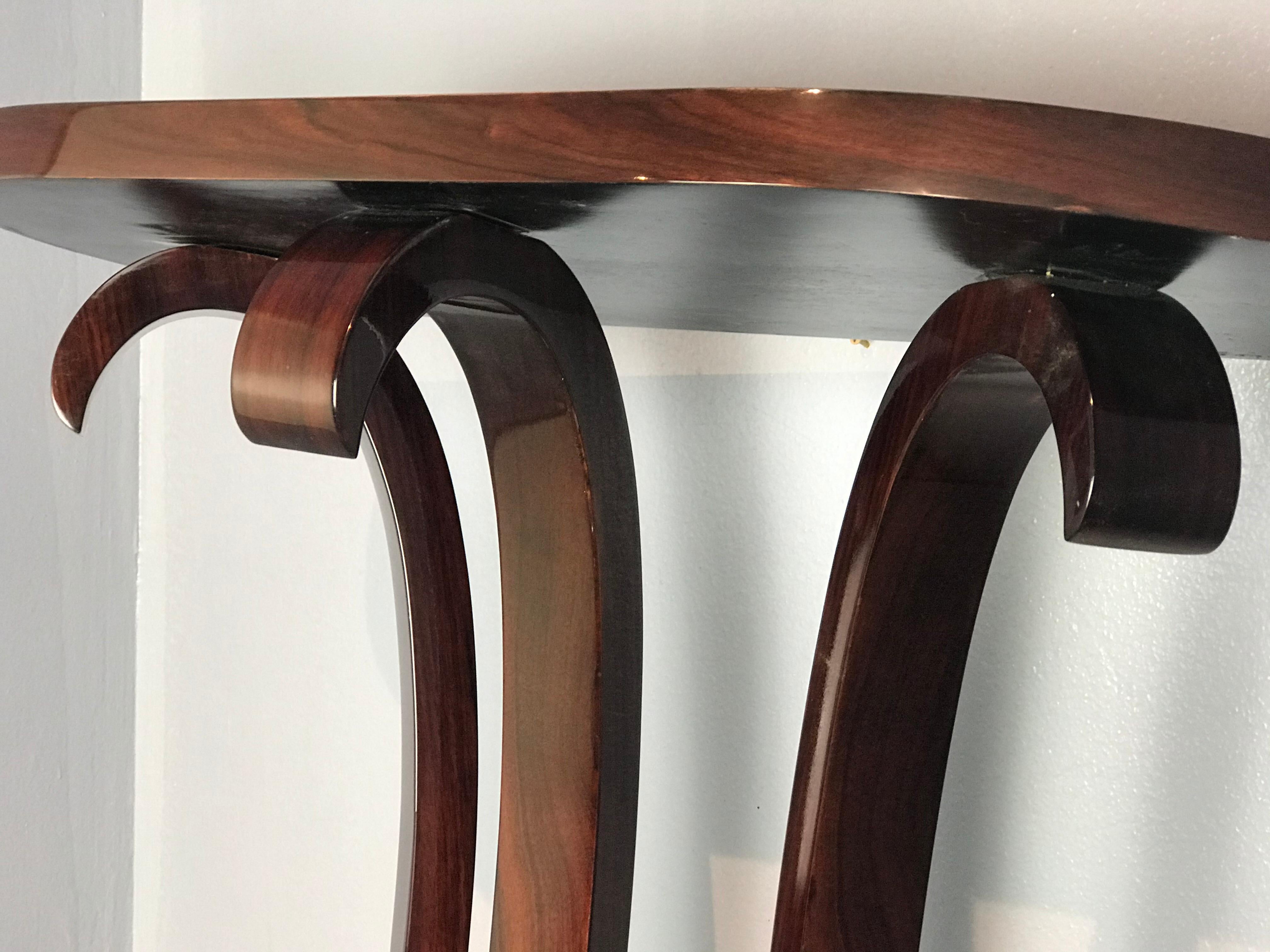 Elegant Art Deco console made of Brazilian rosewood. The top is supported by 3 scrolled legs.
Gloss finish as original.
Very rare size!
It's problably made by Jules Leleu.