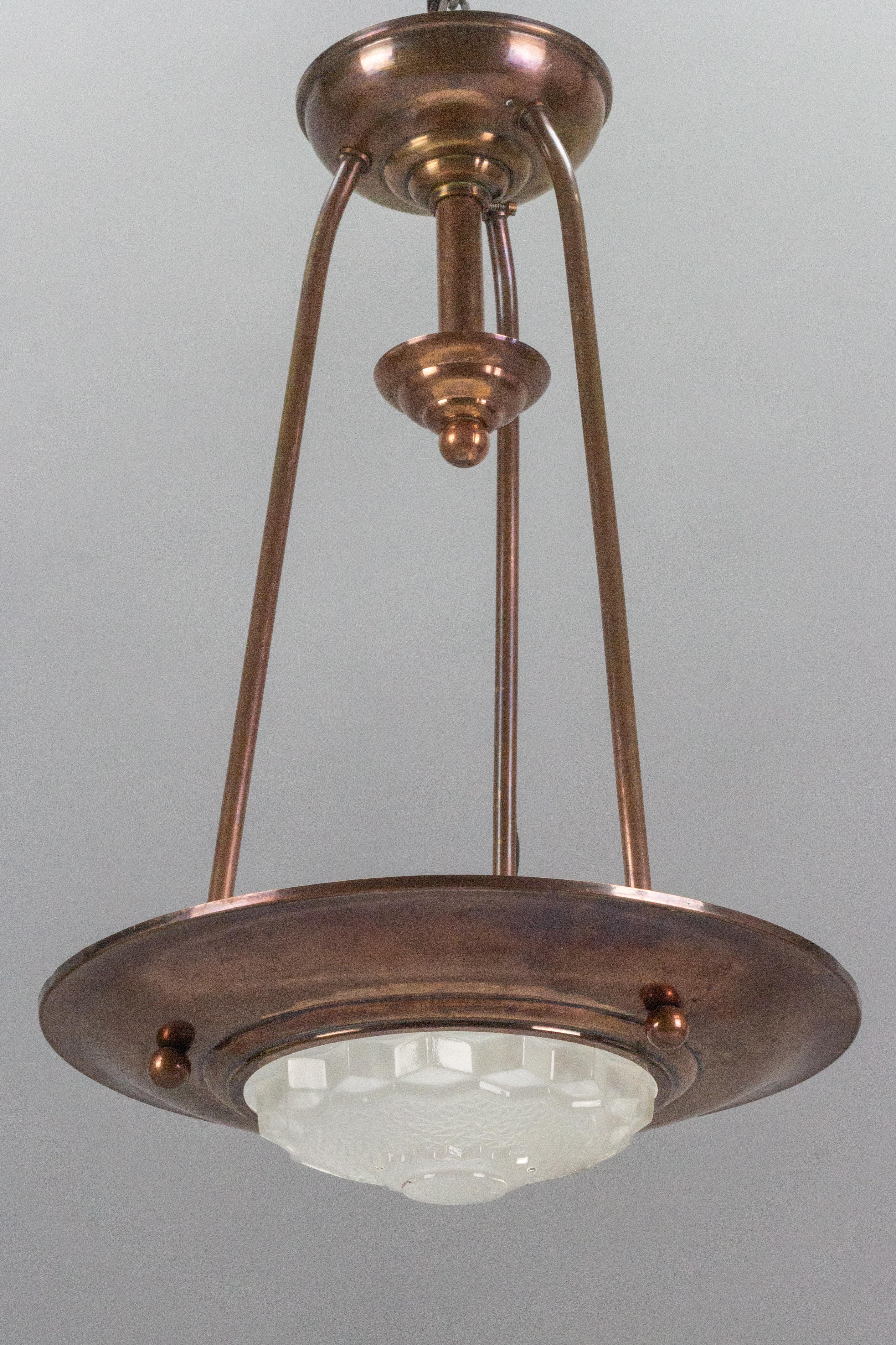 Adorable and compact Art Deco copper and frosted glass pendant light in the style of Ezan, France, 1930s.
One socket for an E14-size light bulb.
Dimensions: height: circa 40 cm / 15.74 in; diameter: 26 cm / 10.23 in.
The light fixture is in complete