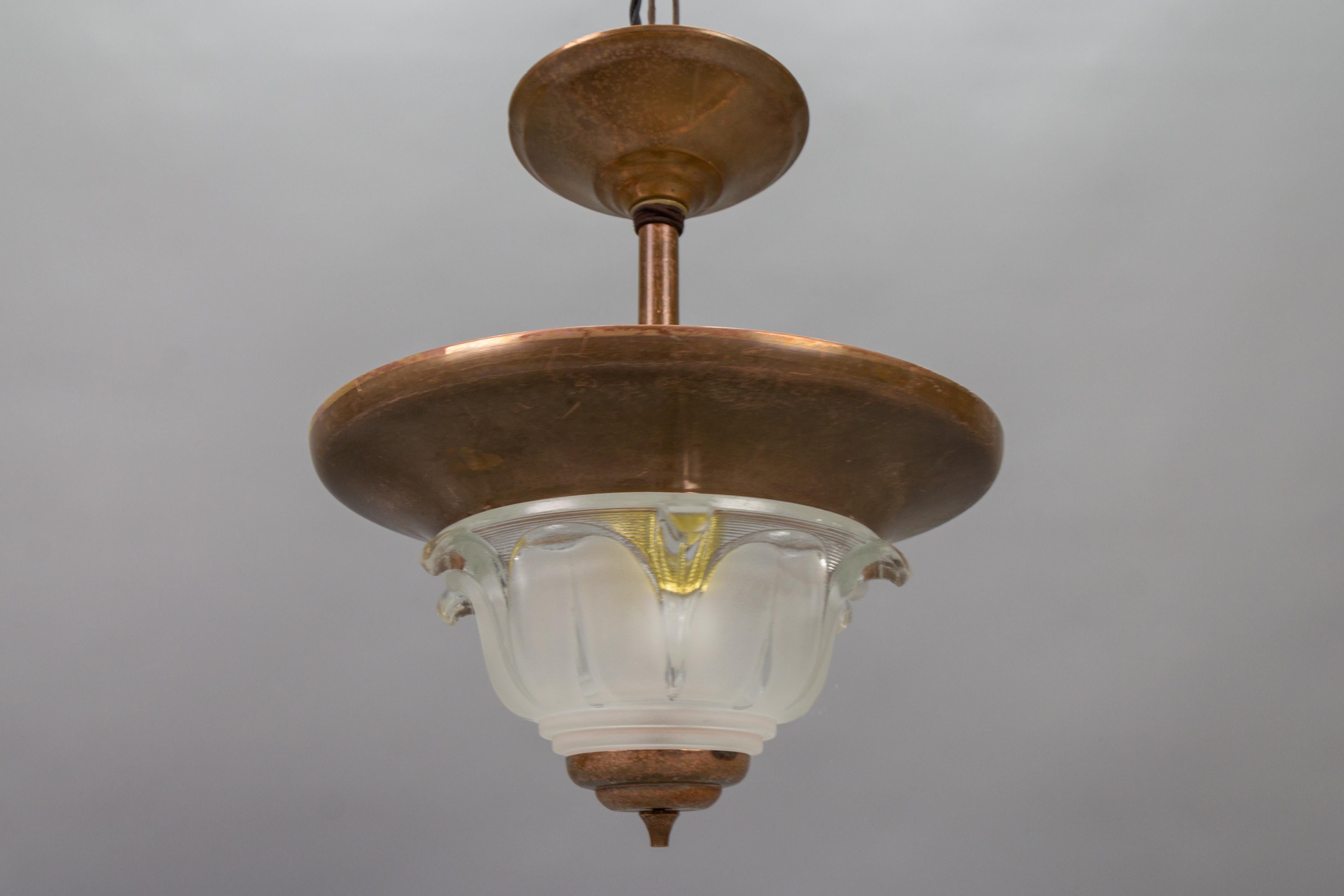 French Art Deco copper and frosted glass pendant light, from circa the 1930s.
Adorable Art Deco two-light ceiling light with copper and metal lamp body and both - white frosted and clear - glass lampshade in the Ezan style. Glass is not signed.
Two