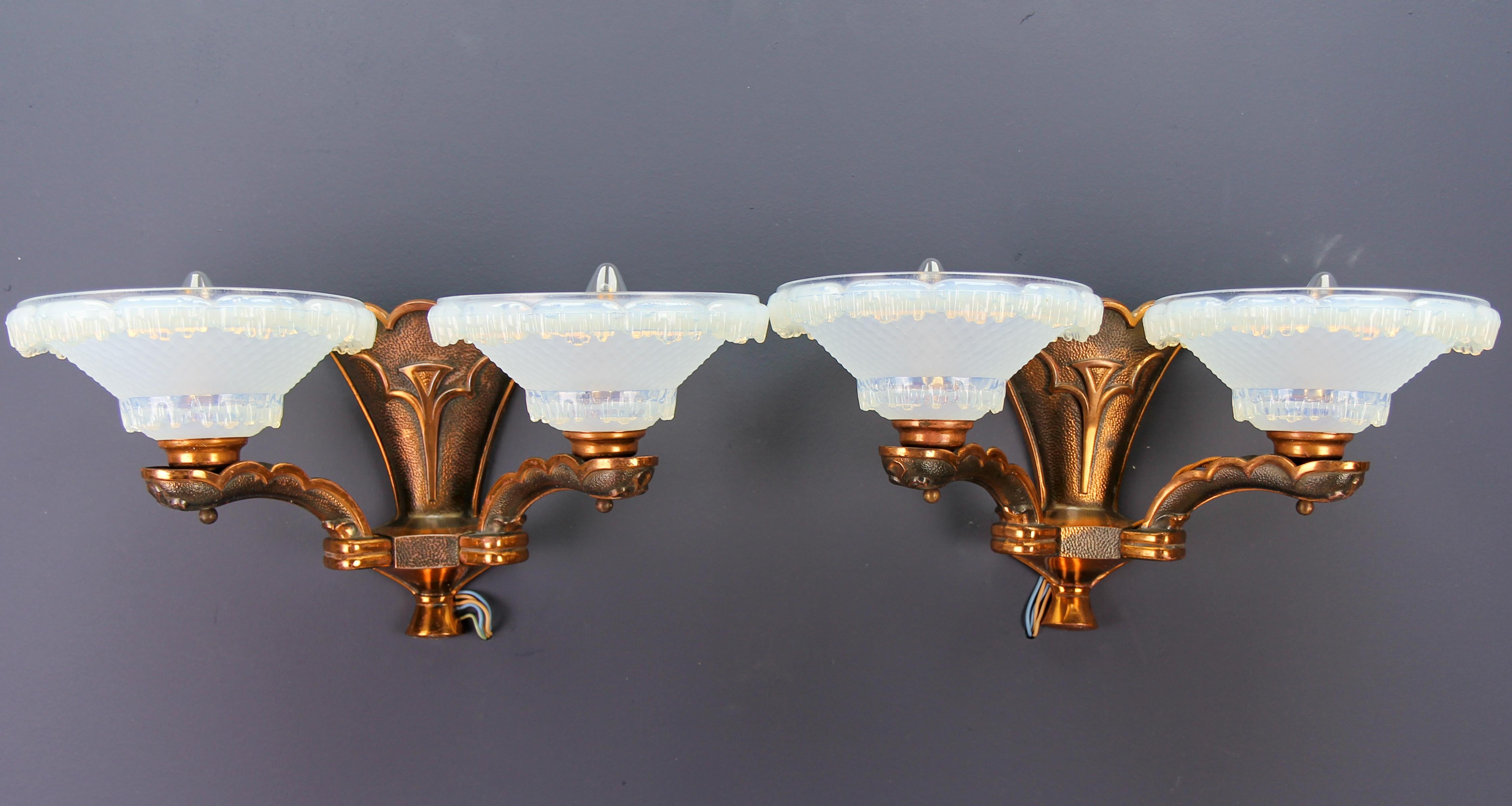 A pair of French Art Deco copper and opalescent glass sconces by Ezan, circa the 1930s.
An impressive pair of French Art Deco copper two-branch sconces each with two opalescent glass shades signed by Ezan.
Each wall lamp has two sockets for