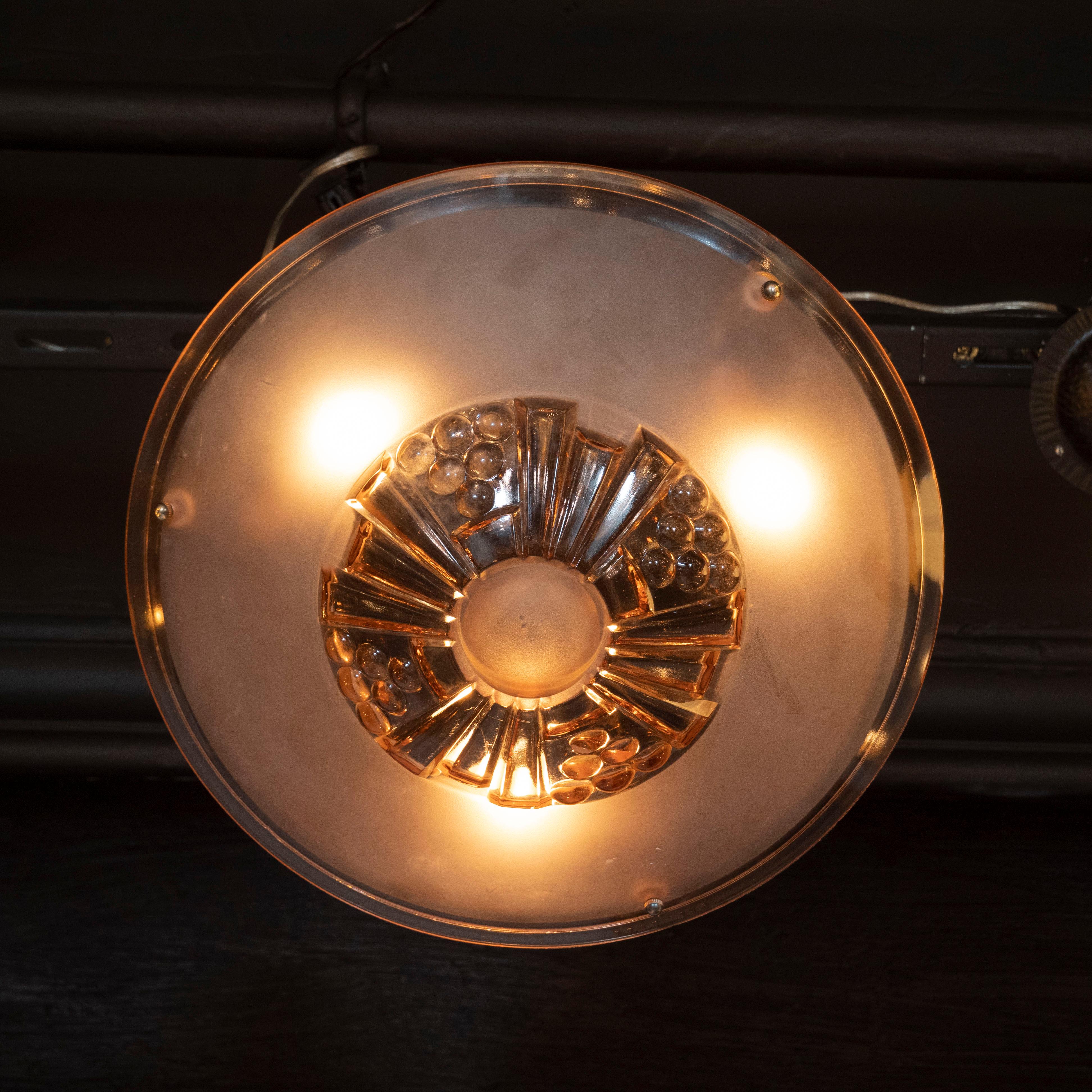 This refined pendant was realized in France, circa 1930. It features a convex body, hand blown in copper hued glass, with geometric cubist motifs including spherical details and skyscraper style fan designs throughout. The glass shade connects to a