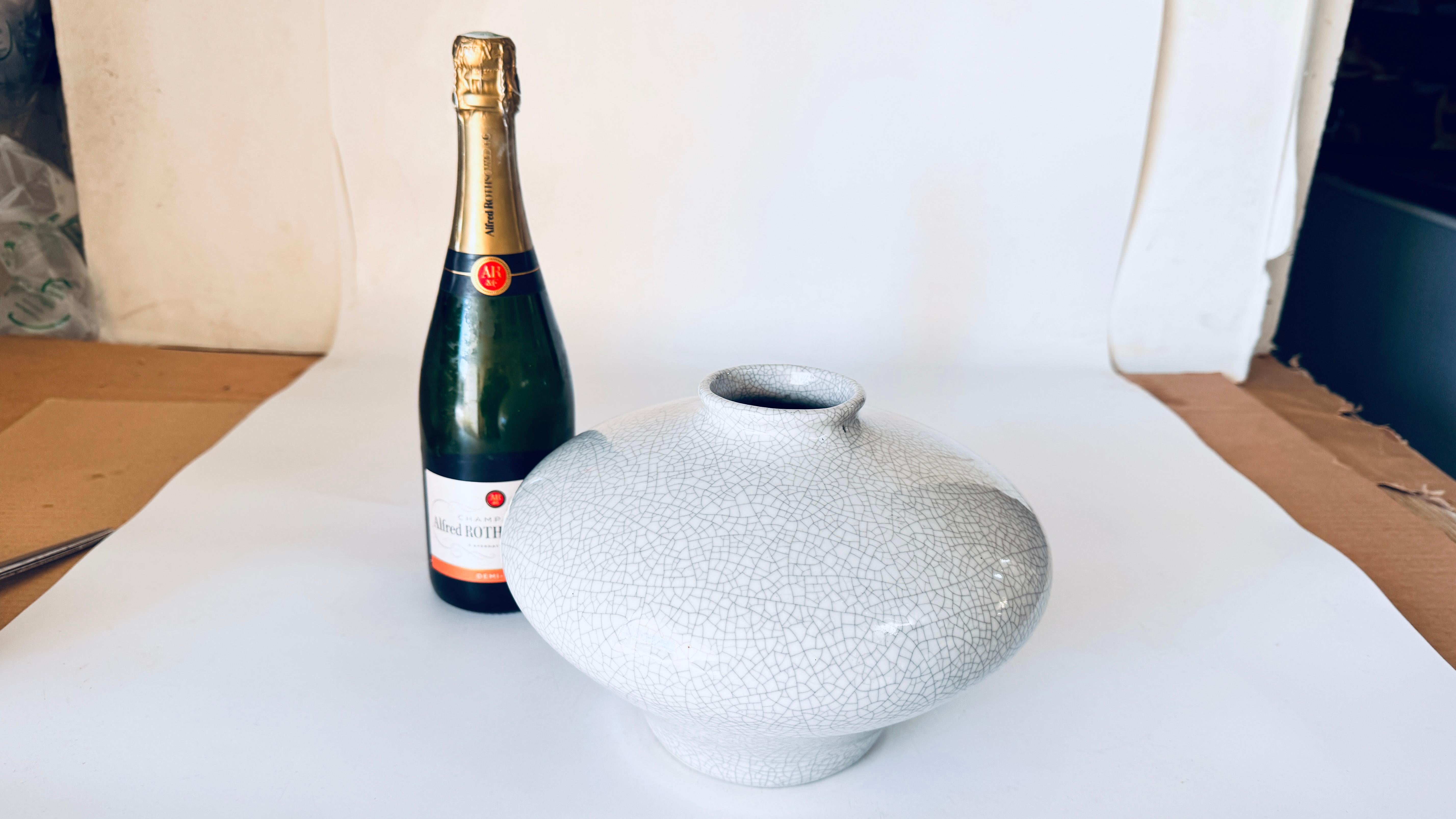 Questo elegante vaso francese in ceramica Art Déco del XX secolo è un bellissimo esempio di design e artigianato senza tempo. La sua forma arrotondata, la base delicatamente svasata e il collo sottile creano una silhouette raffinata, mentre il