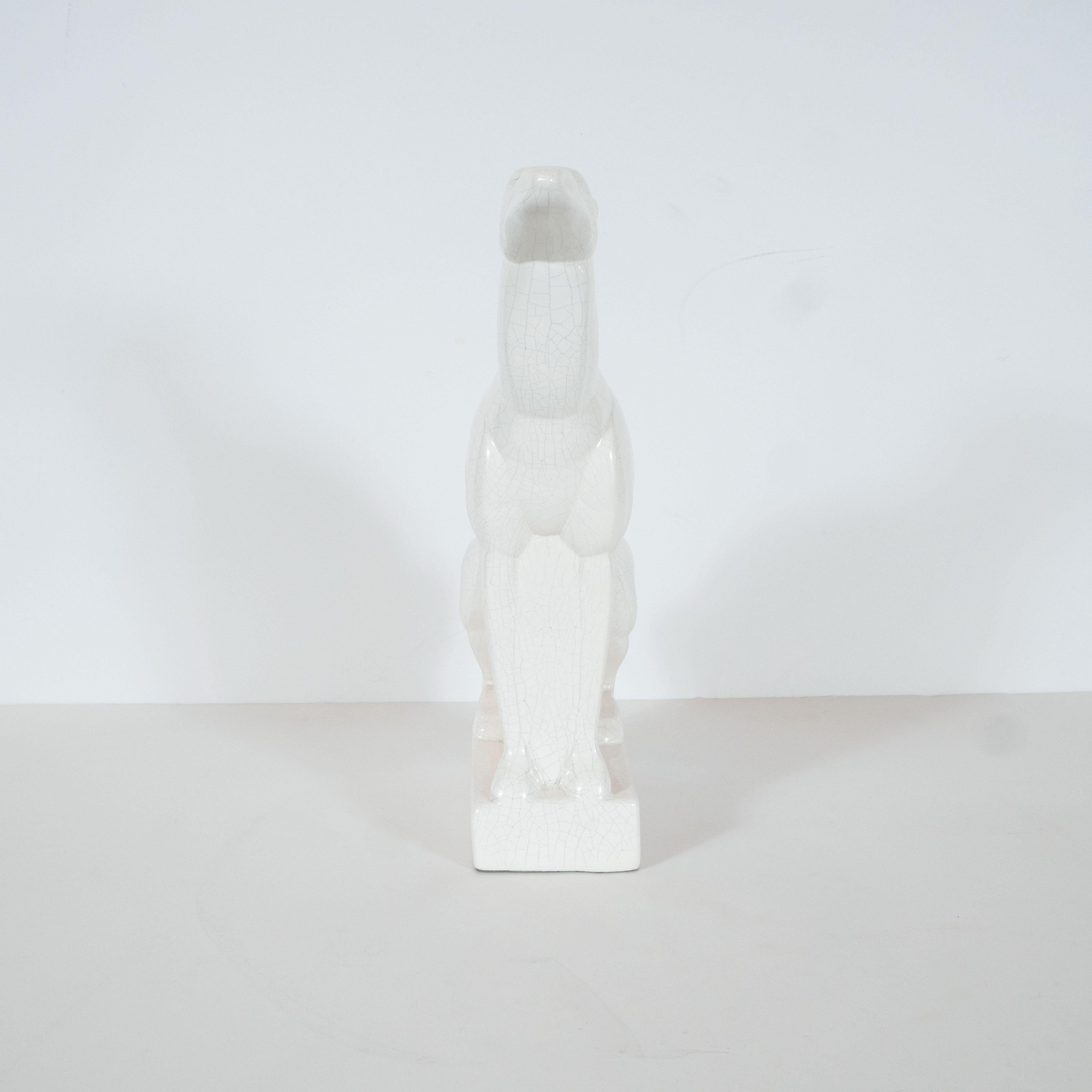 Cette élégante sculpture en céramique Art déco a été réalisée en France, vers 1935. Elle représente une représentation cubiste stylisée d'un lévrier reposant sur ses pattes arrière et ses pattes avant tendues, mettant en valeur sa puissante