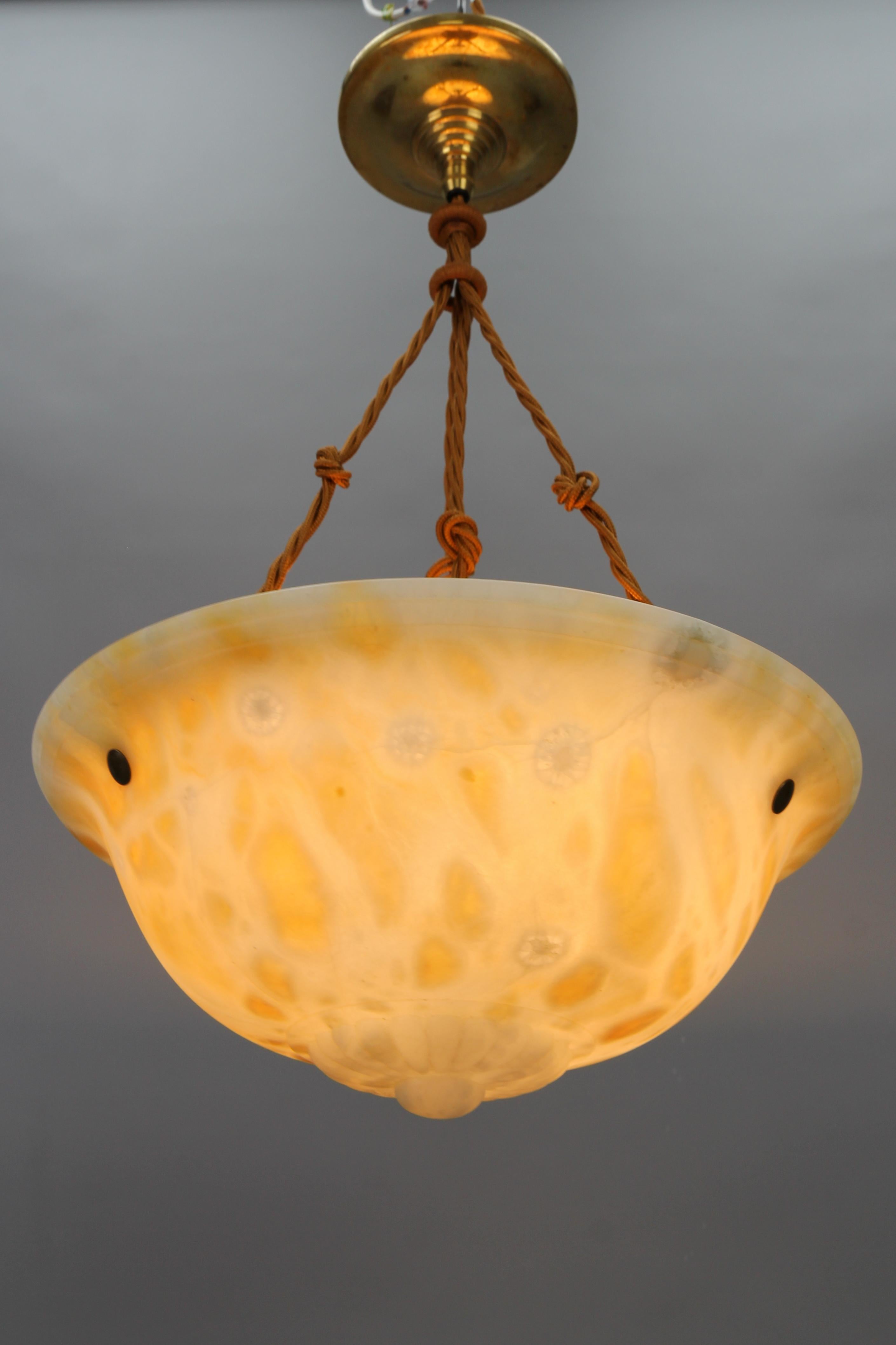 A magnificent Art Deco warm cream color alabaster pendant ceiling light fixture. France, circa the 1930s. 
This beautifully shaped alabaster bowl in warm cream color tones with a flower-shaped finial is suspended by three ropes (wires) and an