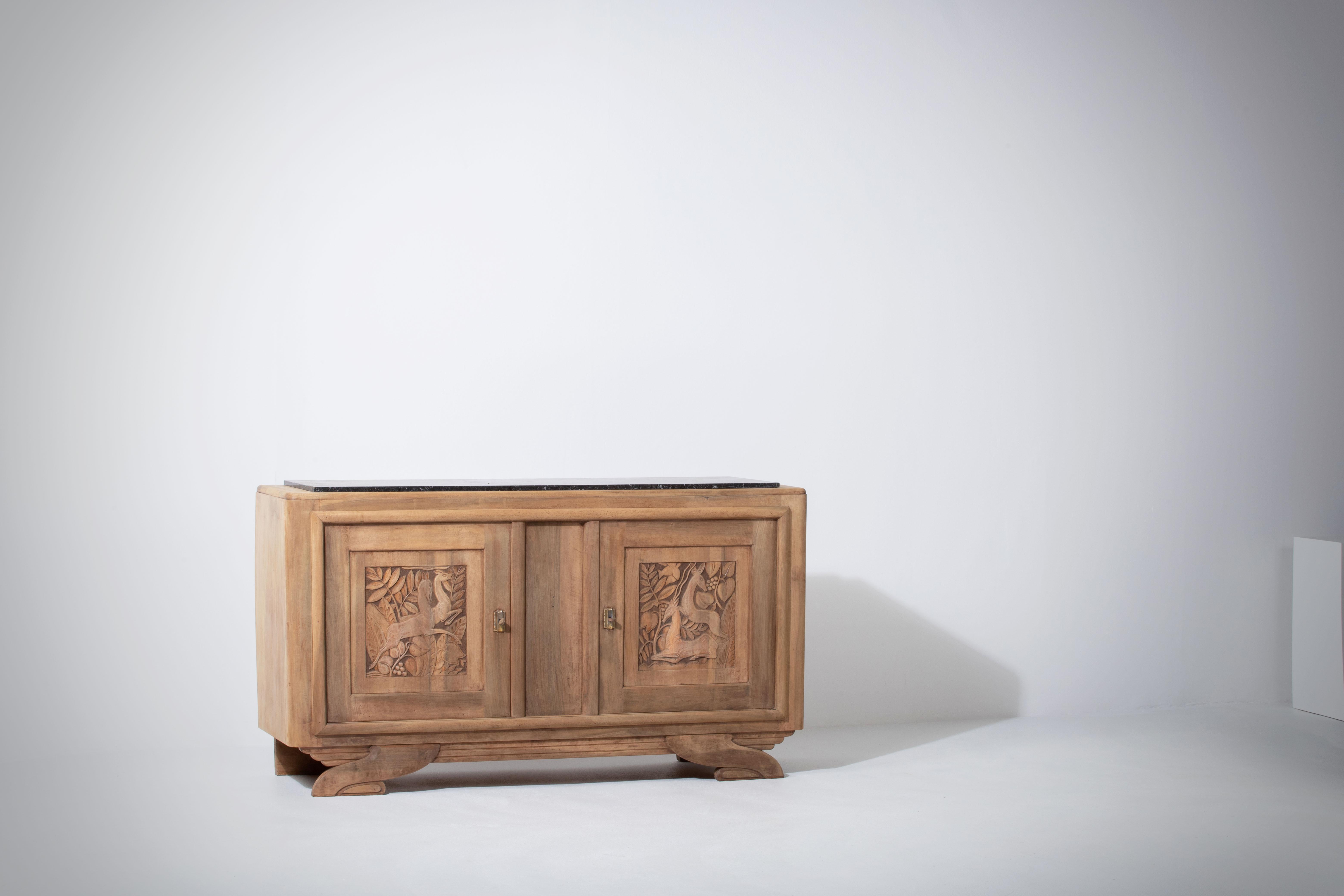 Very elegant credenza in solid oak, France, 1940s.
Art Deco brutalist sideboard. 
The credenza consists of two storage facilities covered with handcarved hunting scene designed doors.
The refined wooden structures on the doors create a striking