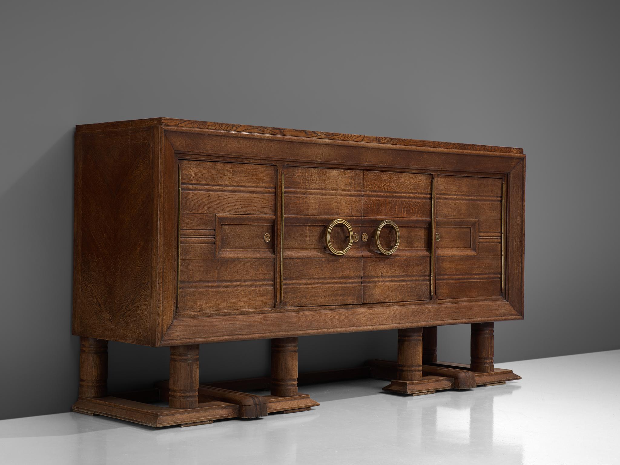 Credenza, oak and brass, France, 1940s.

Large Art Deco sideboard in solid oak with elegant brass details. A well designed piece that is crafted with beautiful elements, for instance geometric engraved front. The sideboard contains plenty of storage
