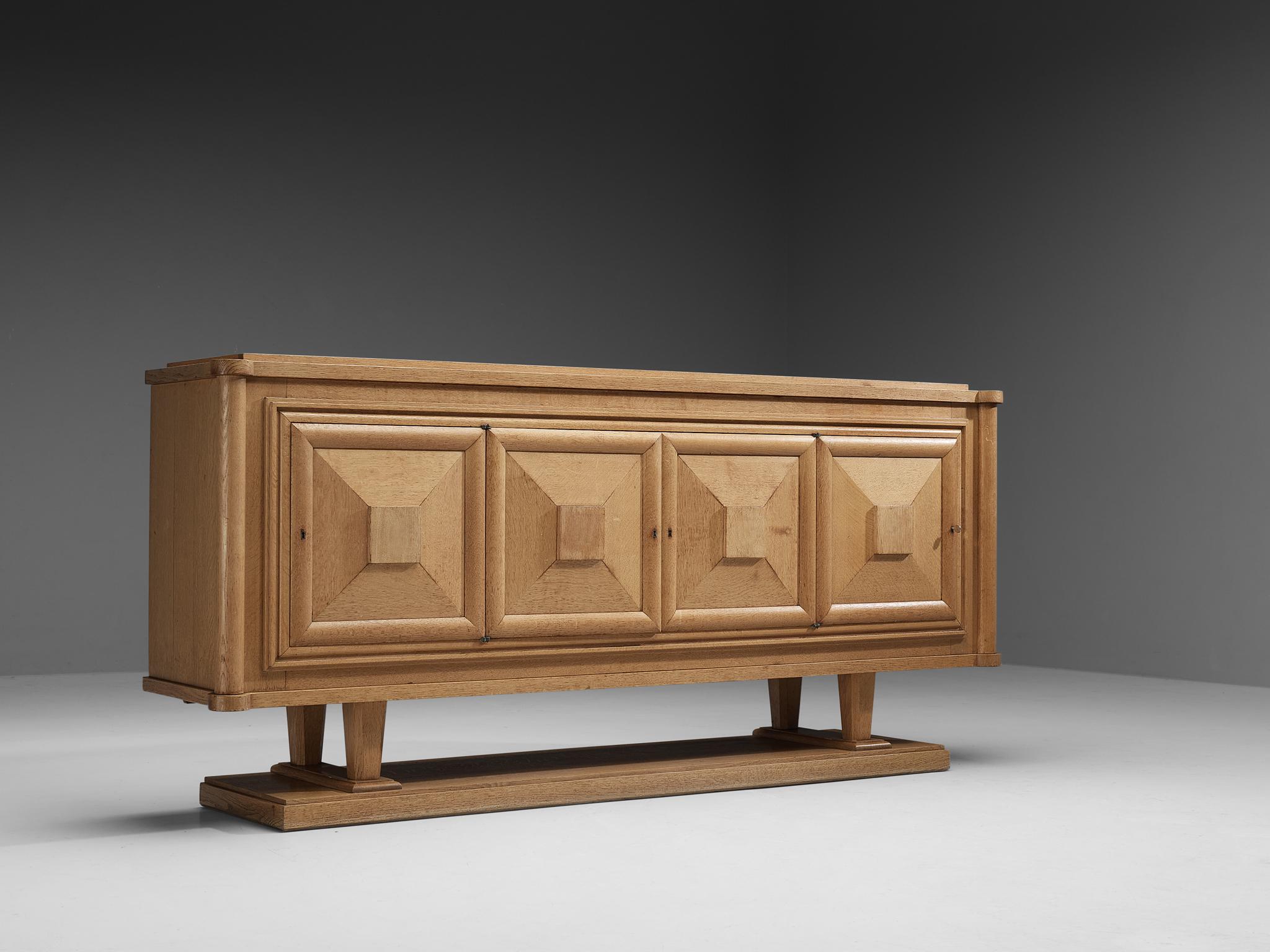 Sideboard, oak, France 1930s.

Large Art Deco credenza in oak. The sideboard has four doors, all with beautifully designed wooden graphical patterns. The diagonal lines with added squares and a frame emphasize the three-dimensional character of