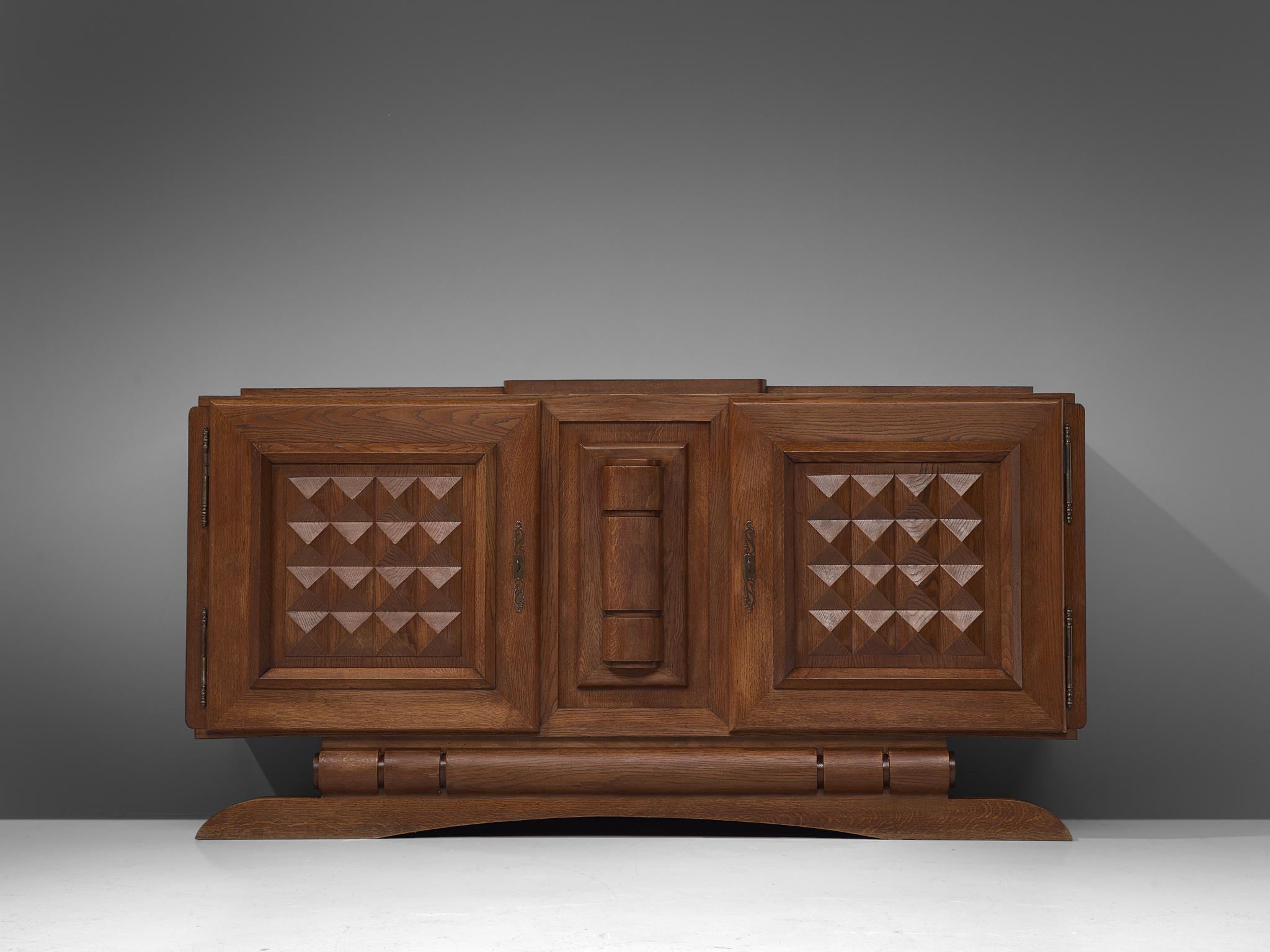 Credenza, stained oak, France, 1940s

Sturdy sideboard in oak with graphical door panels. The sideboard is equipped with several shelves behind the two doors that are finished with a graphical inlay. The door panels and base details are stunning and