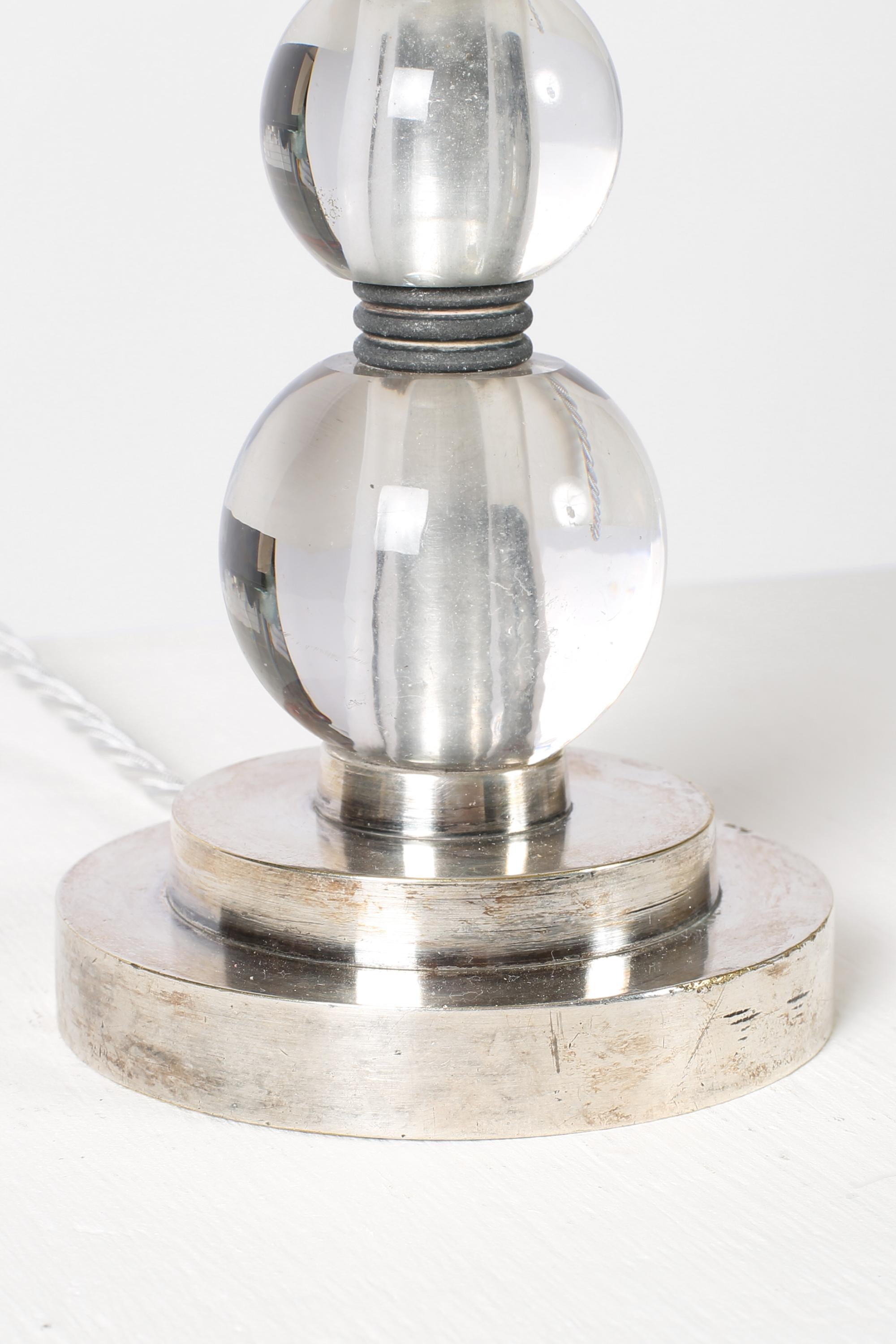 An Art Deco table lamp in nickel-plated bronze with three stacked crystal glass ‘boules’, very much in the manner of Jacques Adnet (1900-1984). French, c. 1930s. Supplied with a bespoke off-white dupion silk shade.