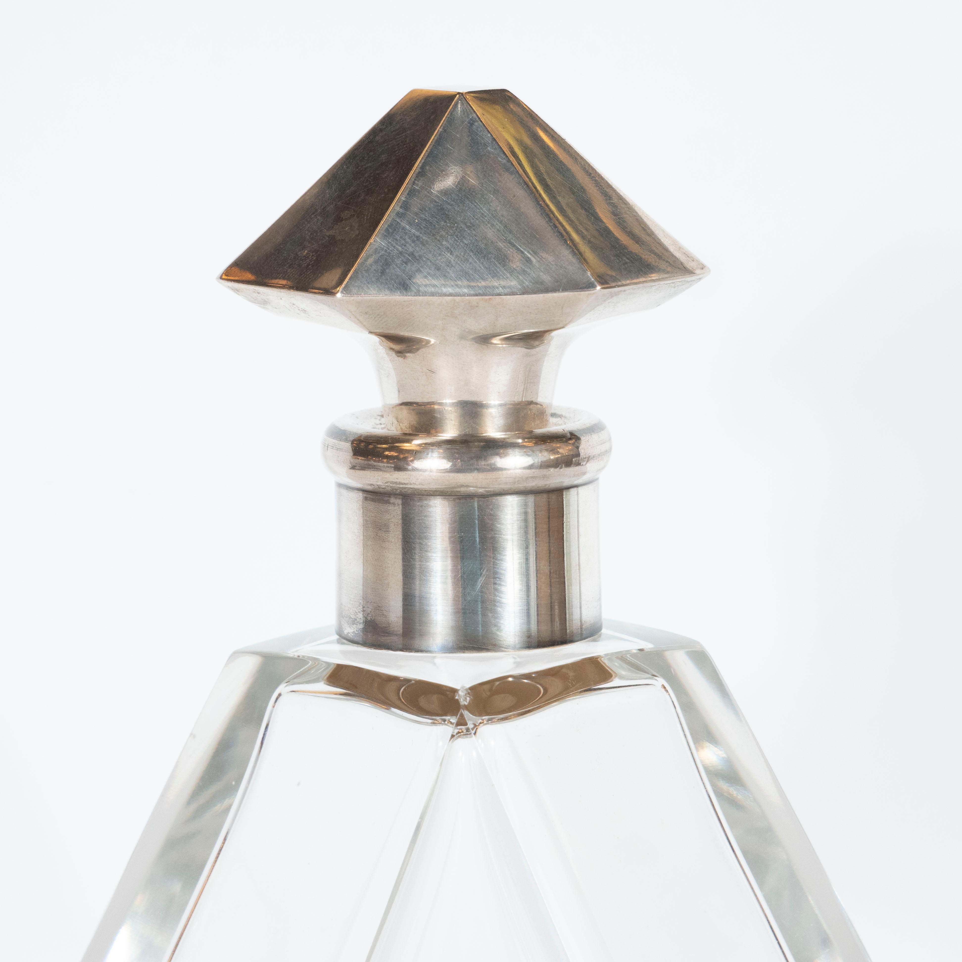 This elegant cubist crystal decanter was realized in France, circa 1935. It features a faceted and elongated hexagonal form that tapers to flat shoulders in a diamond shape at its apex from its widest point near the bottom. A cylindrical neck, in