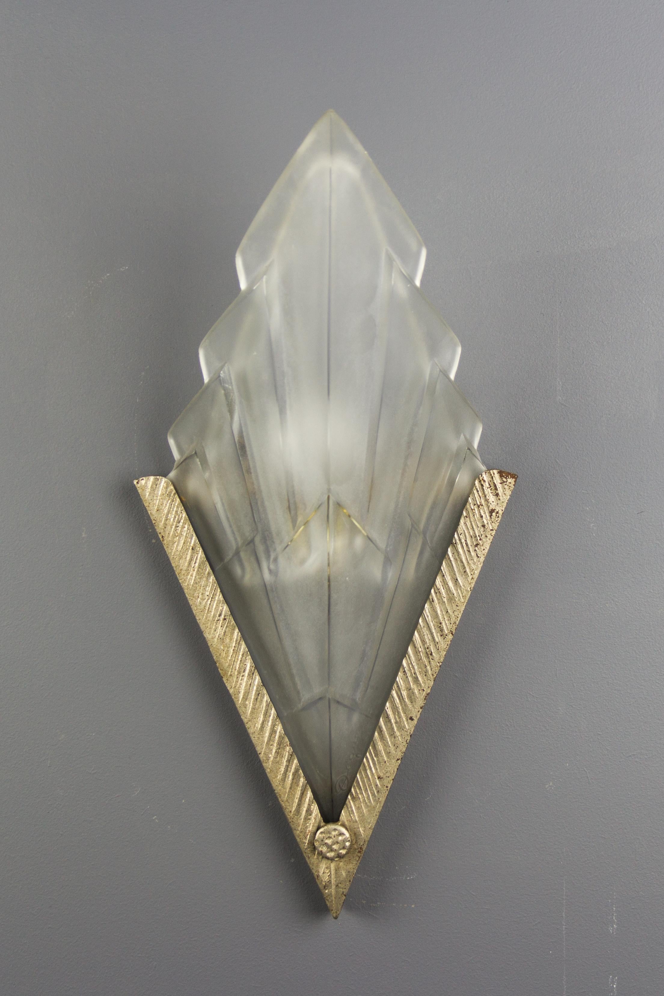 An Art Deco wall light, designed by David Gueron, signed in the glass with Degué and marked Compiegne France. Frosted glass shade mounted in a silver-colored wrought iron holder. One socket for the E14 light bulb.
Dimensions: height 39 cm / 15.35