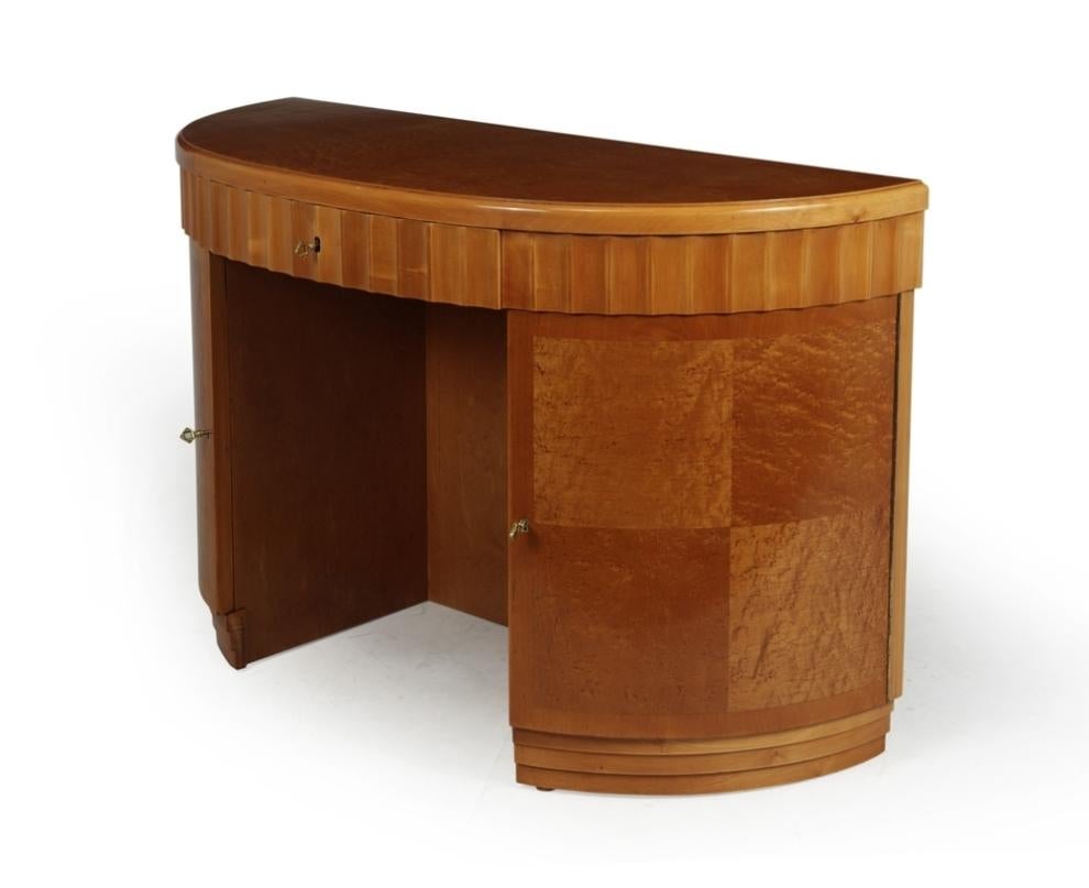A French art deco demi-lune desk in birds eye maple and cherry with fluted apron, central lockable drawer and two curved doors below are also lockable with shelves behind, all locks work and have keys, the desk has been fully polished and is in