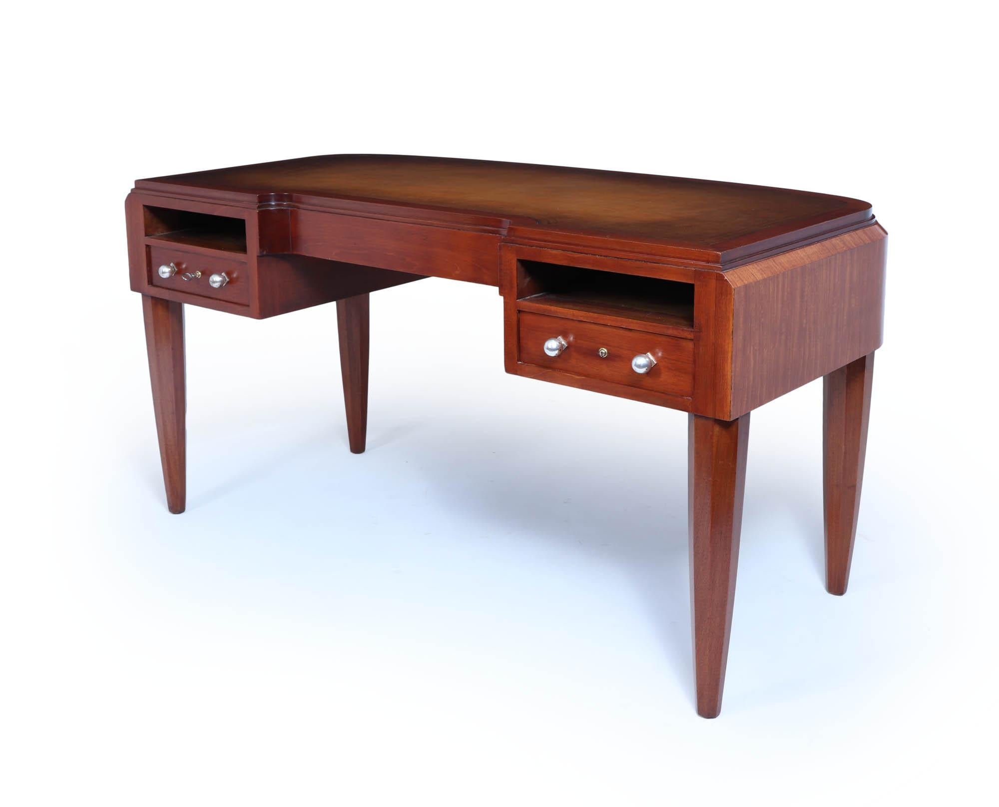 Scrivania francese Art Deco 
Una scrivania art déco francese di qualità eccezionale, prodotta negli anni '20 in mogano e legno di raso.  Piano con inserti in pelle, due cassetti con serratura, maniglie argentate, schienale curvo e gambe ottagonali