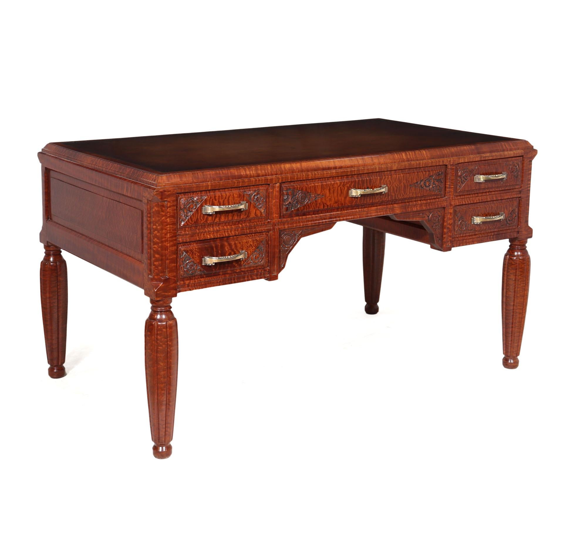 An exceptional quality French Art Deco desk, produced around 1925 using solid Pomelle Sapele the desk has five drawers with bronze handles and crisply carved detail, the desk is freestanding and has panelled rear to match the front and stands on a