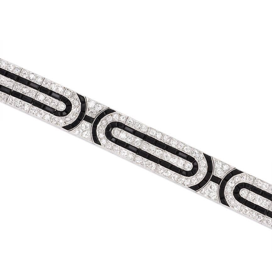 An Art Deco diamond bracelet set with calibre onyx in a geometric pattern of oblong motifs, in platinum.  France.  Atw 8.50 cts. diamonds.