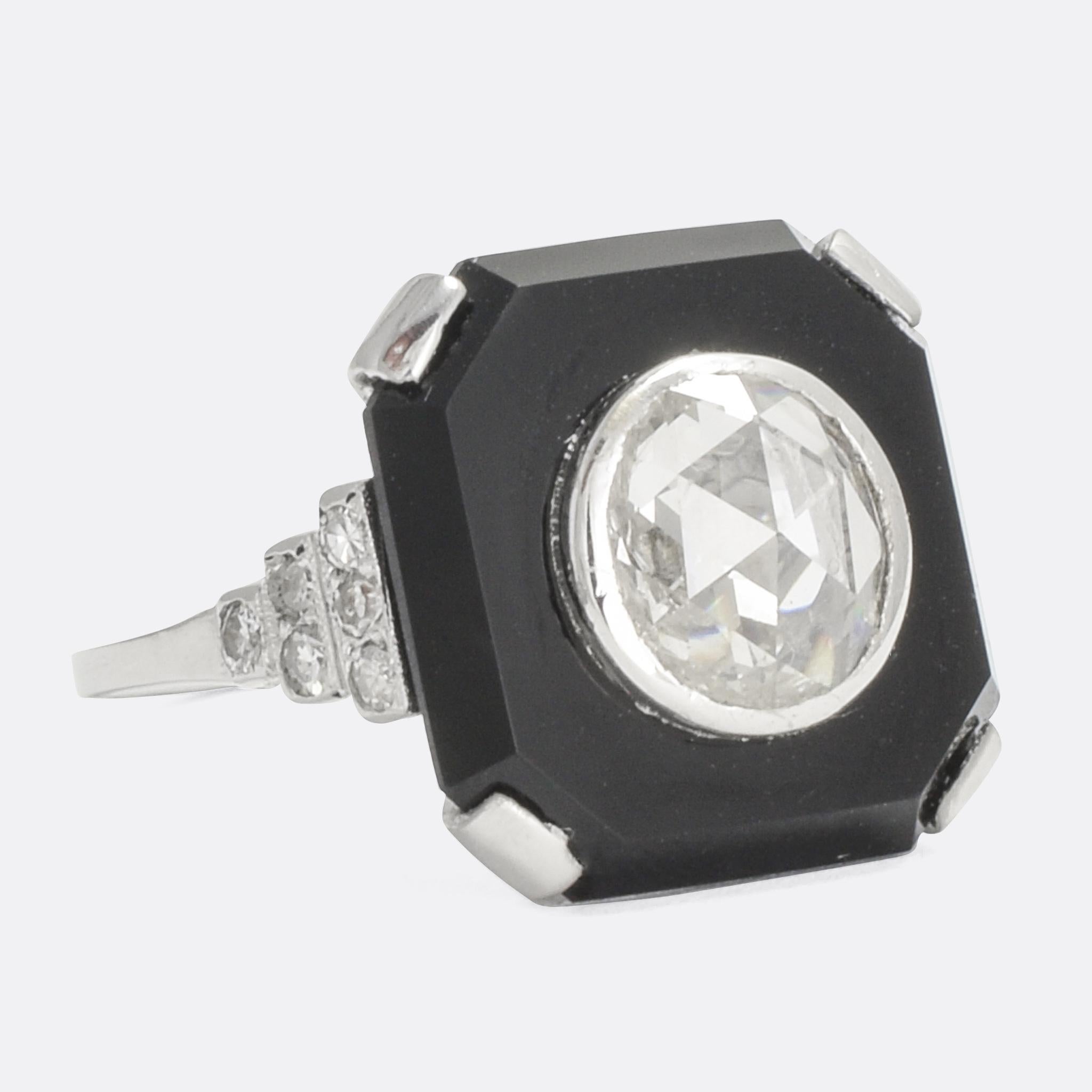 A stunning French Art Deco ring. The large domed rose cut diamond is set such that it appears to float within a black onyx slab. With stepped diamond shoulders and an openworked gallery complete the striking design. It's modelled in platinum