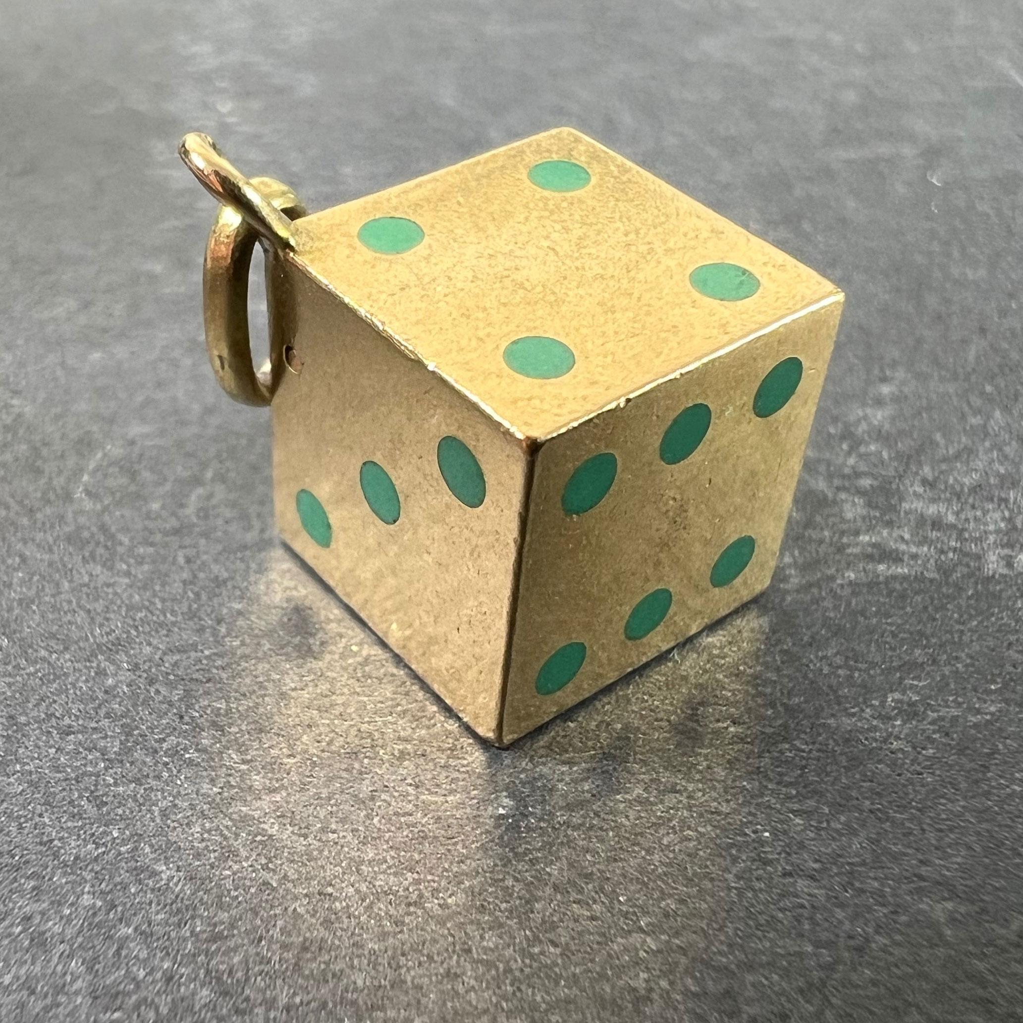 A French Art Deco 18 karat (18K) yellow gold charm pendant designed as a six-sided die set with turquoise blue enamel to the pips. The box opens to reveal three miniature dice in a creamy-white material with black pips. Stamped with the eagle's head