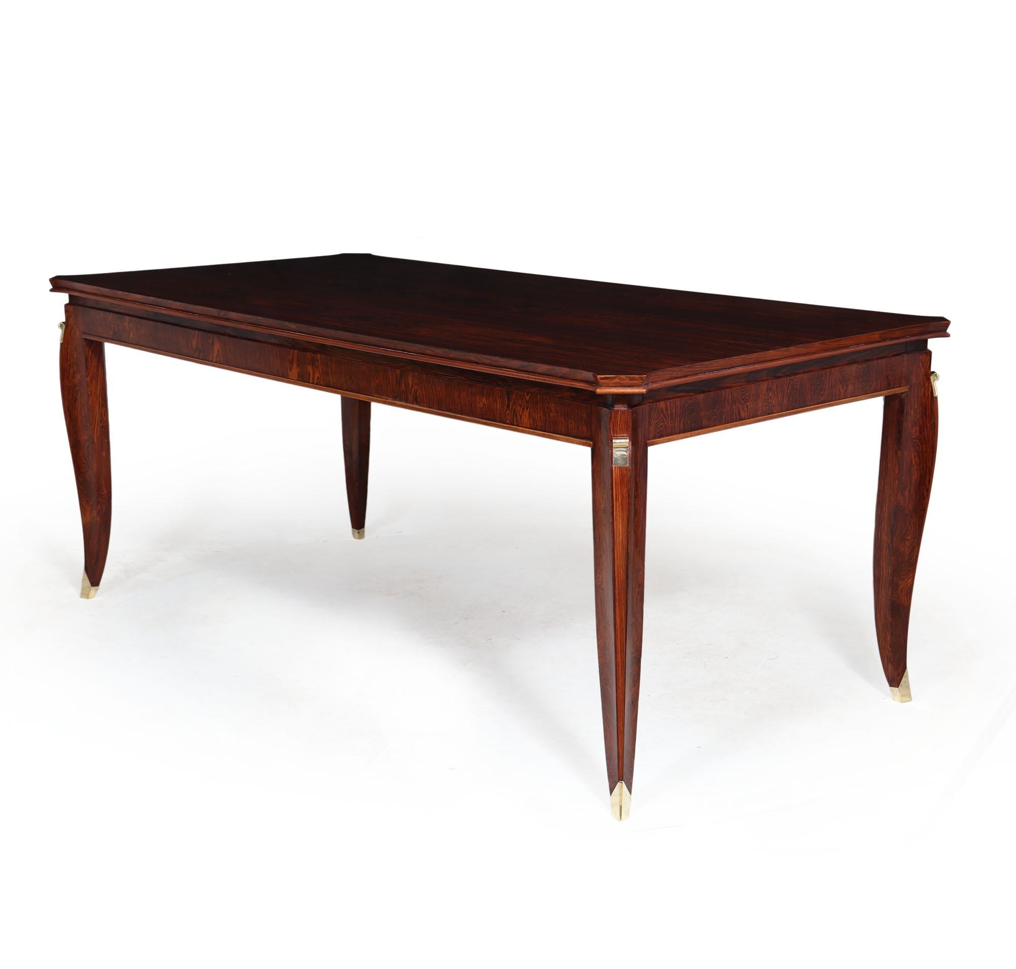 Exceptional quality French Art Deco dining table by Maurice Rinck, produced in solid oak with rosewood veneer and bronze sabots and fittings. The table will seat 8 without the leaves and 10-12 with. The table has been professionally polished and is