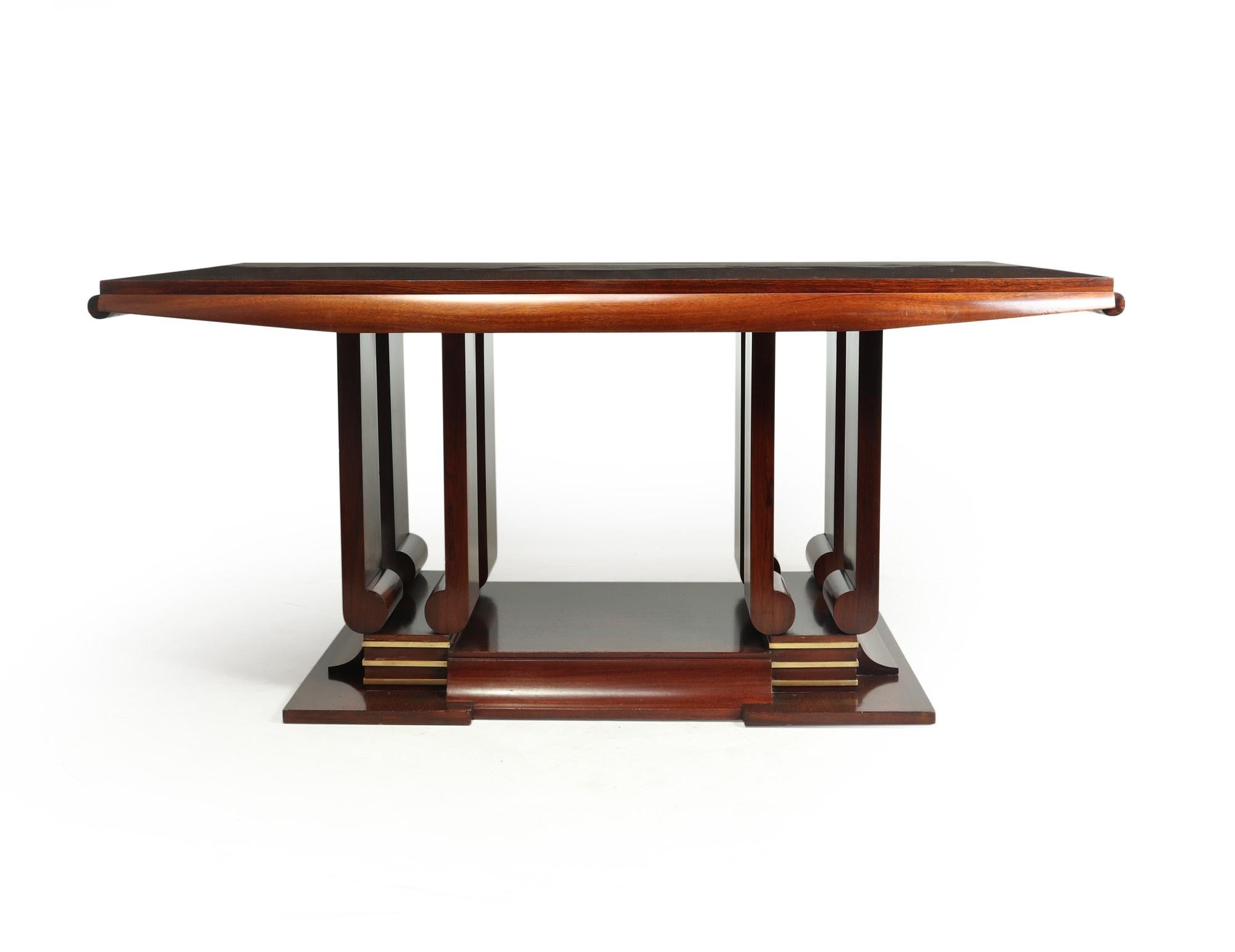 An extendable dining table produced in France in the 1930’s in rosewood on oak, a stunning centre column with heavy brass detail around the lower section, the top extends either ender to seat up to four more people.

The table is extremly well