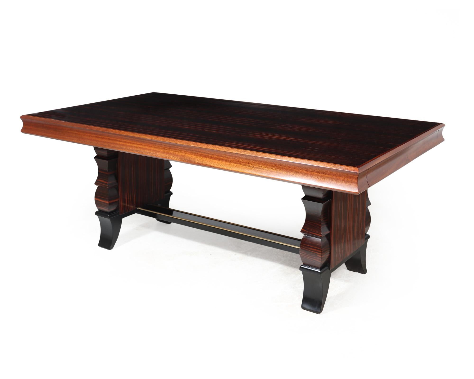 FRENCH ART DECO DINING TABLE 
This elegant French art deco extending dining table was crafted in France during the 1920s, featuring a combination of Macassar ebony and mahogany. Supported by an intricately designed twin pedestal base with brass
