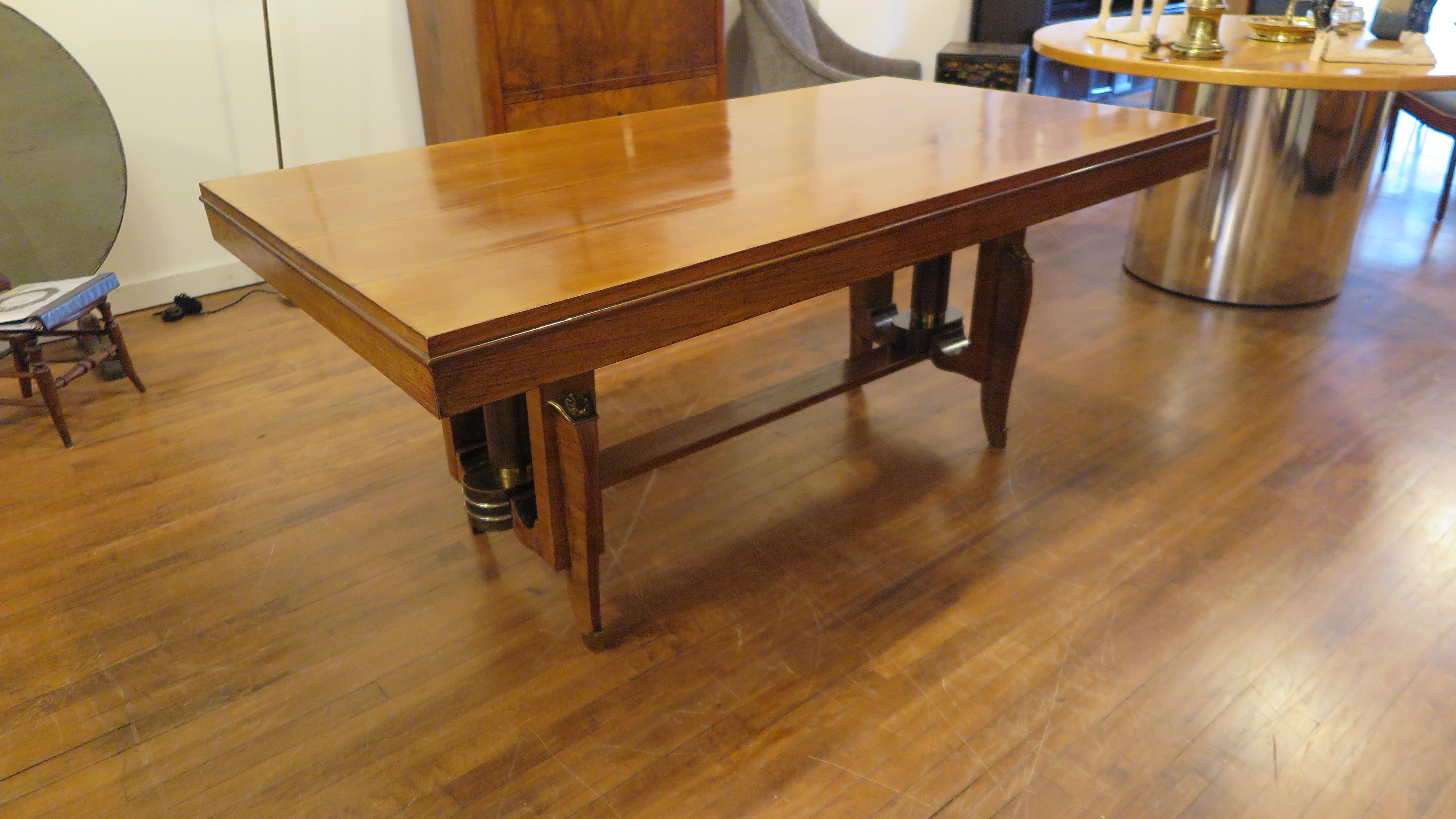 French Art Deco dinning table in the style of Jules Leleu. Extension table having cabriole legs with banding supported by trestle with columns adorned with brass details. There are two drawers that pull out, one on each end of the table. The drawers