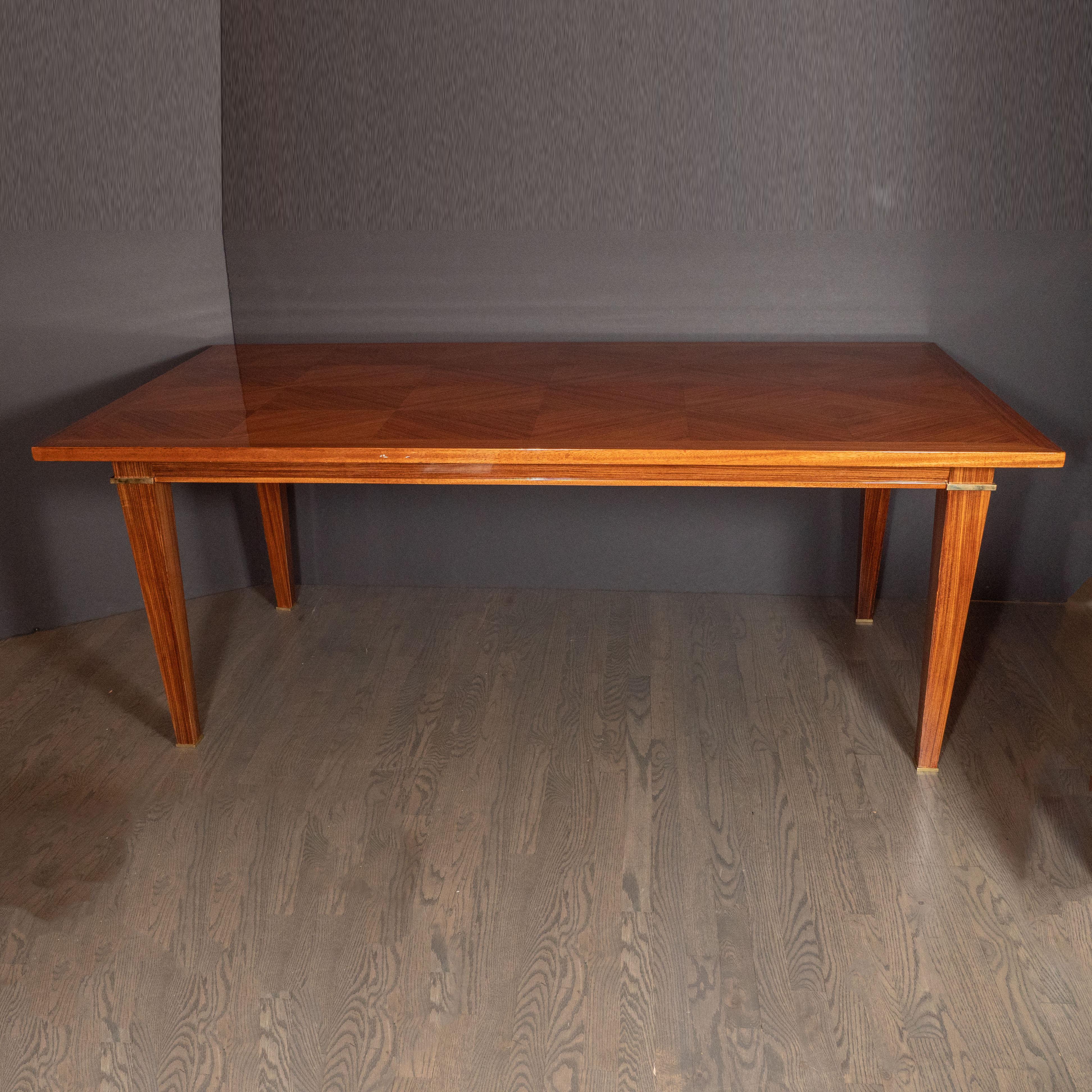 This elegant Art Deco Directoire style table was crafted in France, circa 1940. It features a stunning walnut top- the woodgrain has been bookmatched to form a stunning mosaic of geometric triangular forms bordered along the perimeter by bands of