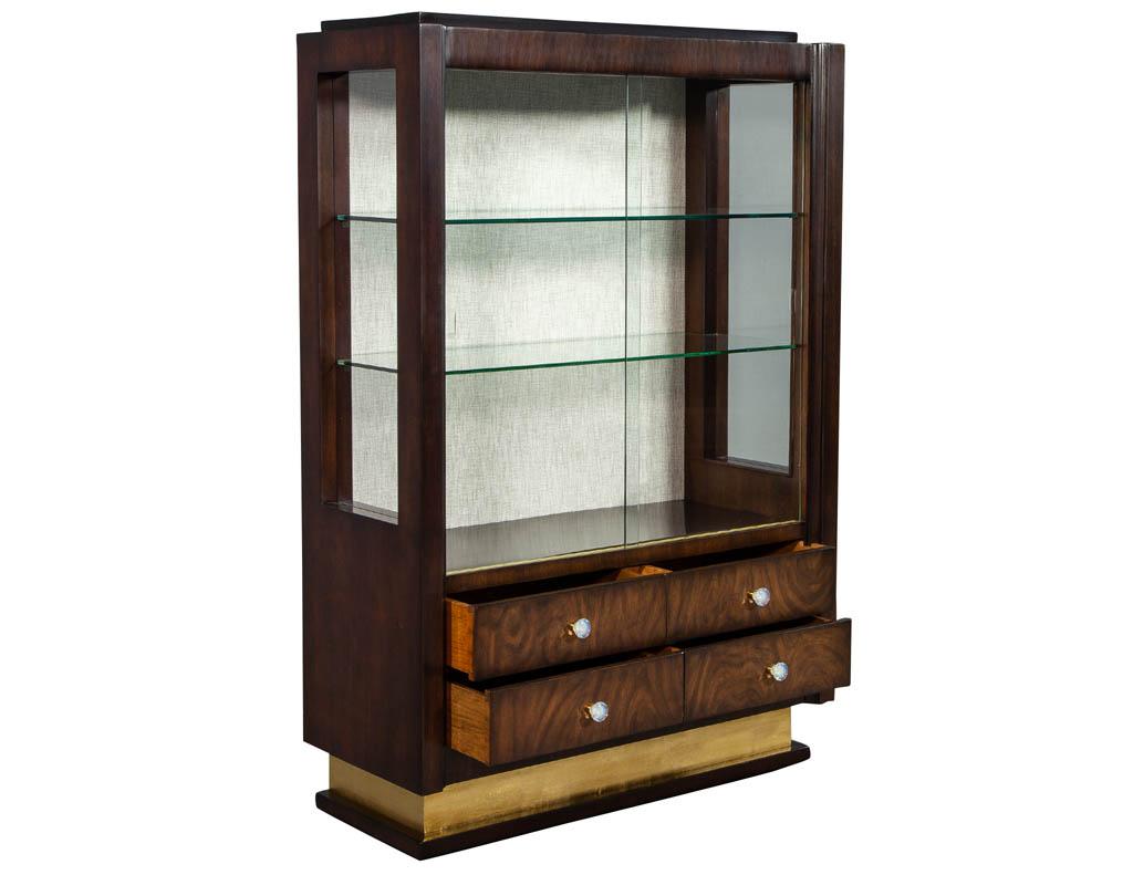 Unique French Art Deco display cabinet, recently restored by our master finishers in a rich chestnut hand rubbed finish. Featuring all original hardware pulls, sliding glass doors and shelves. Base is gold leafed.